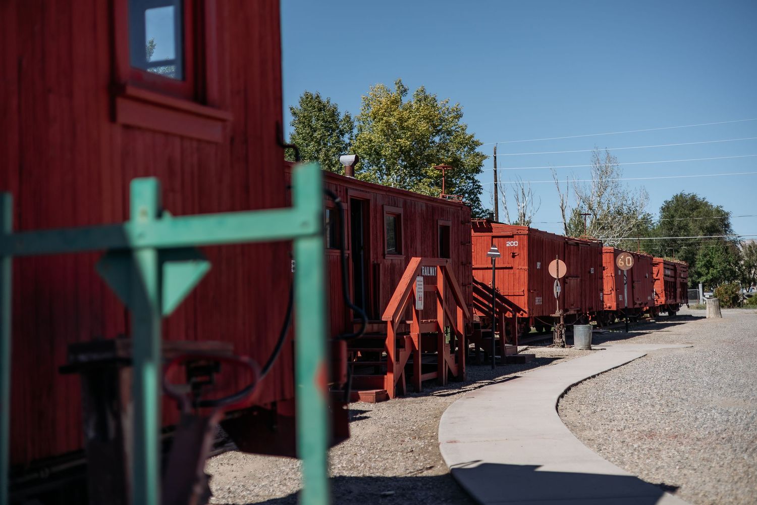A long line of red freight train cars curves along a railway track on a sunny day.