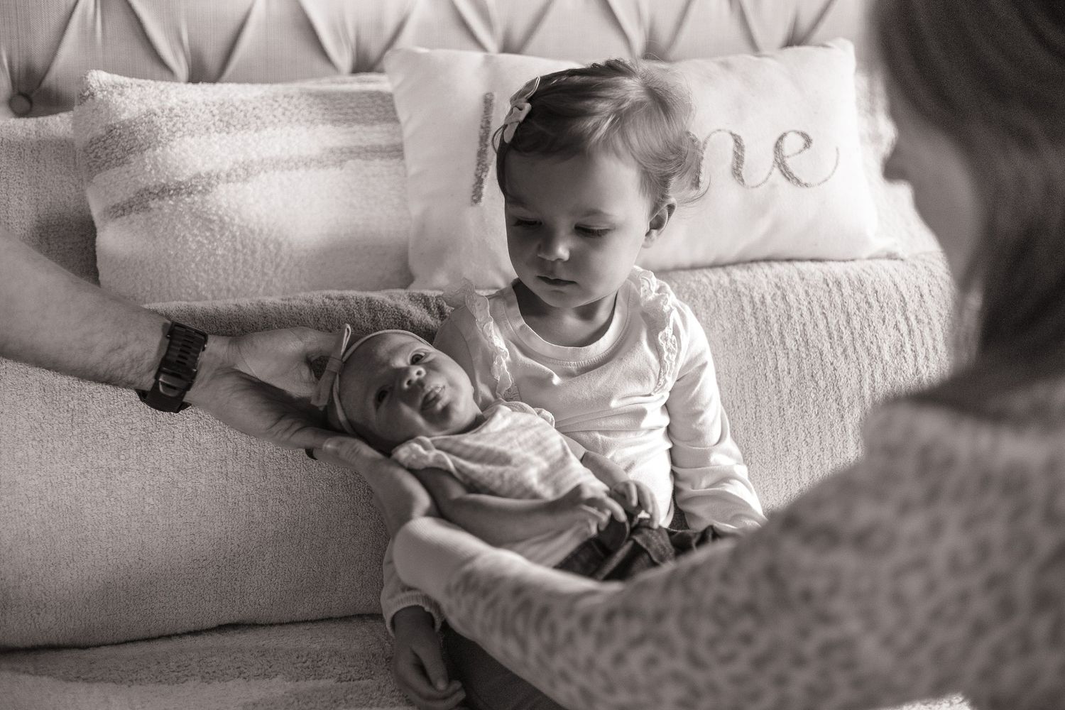 Close-up black and white photo showing hands gently cradled against a sweater in an intimate moment of rest.