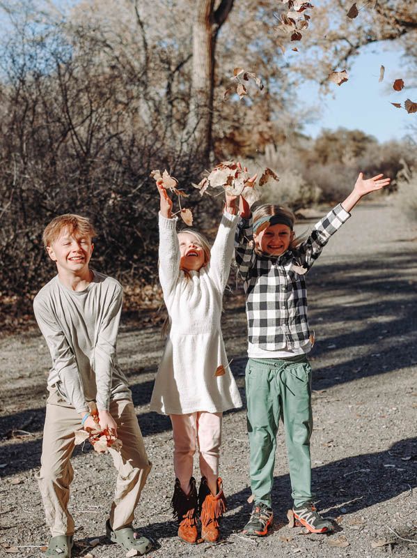 Children playing and throwing autumn leaves in the air at Connected Lakes, Grand Junction, Colorado.