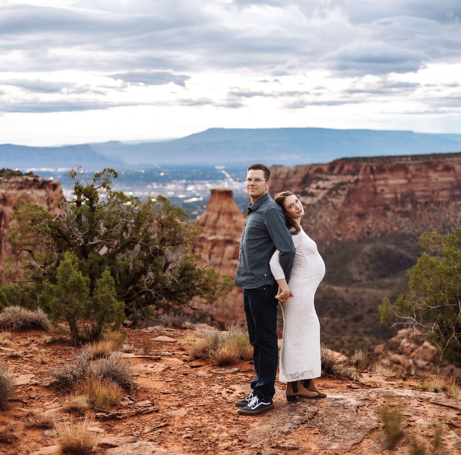 A couple shares an intimate moment at the edge of a scenic canyon overlook during sunset.
