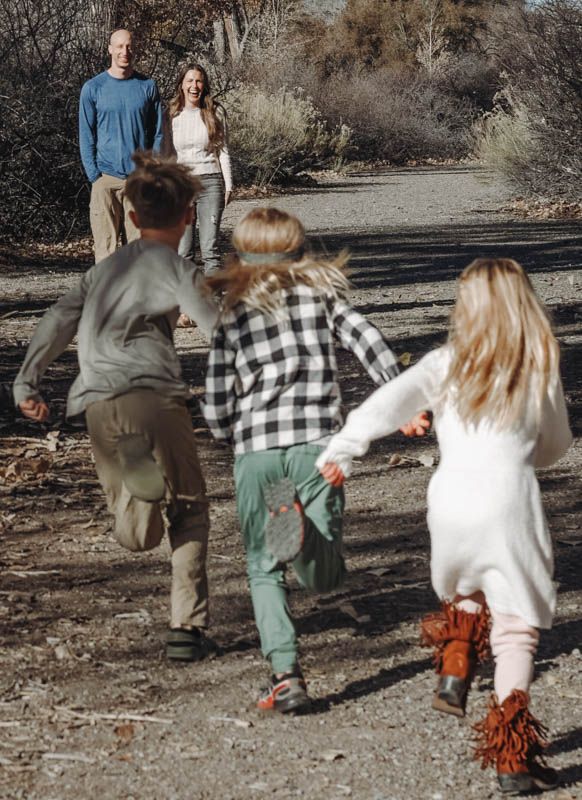 A family walking together along a dusty trail in casual outdoor attire during a sunny autumn day.