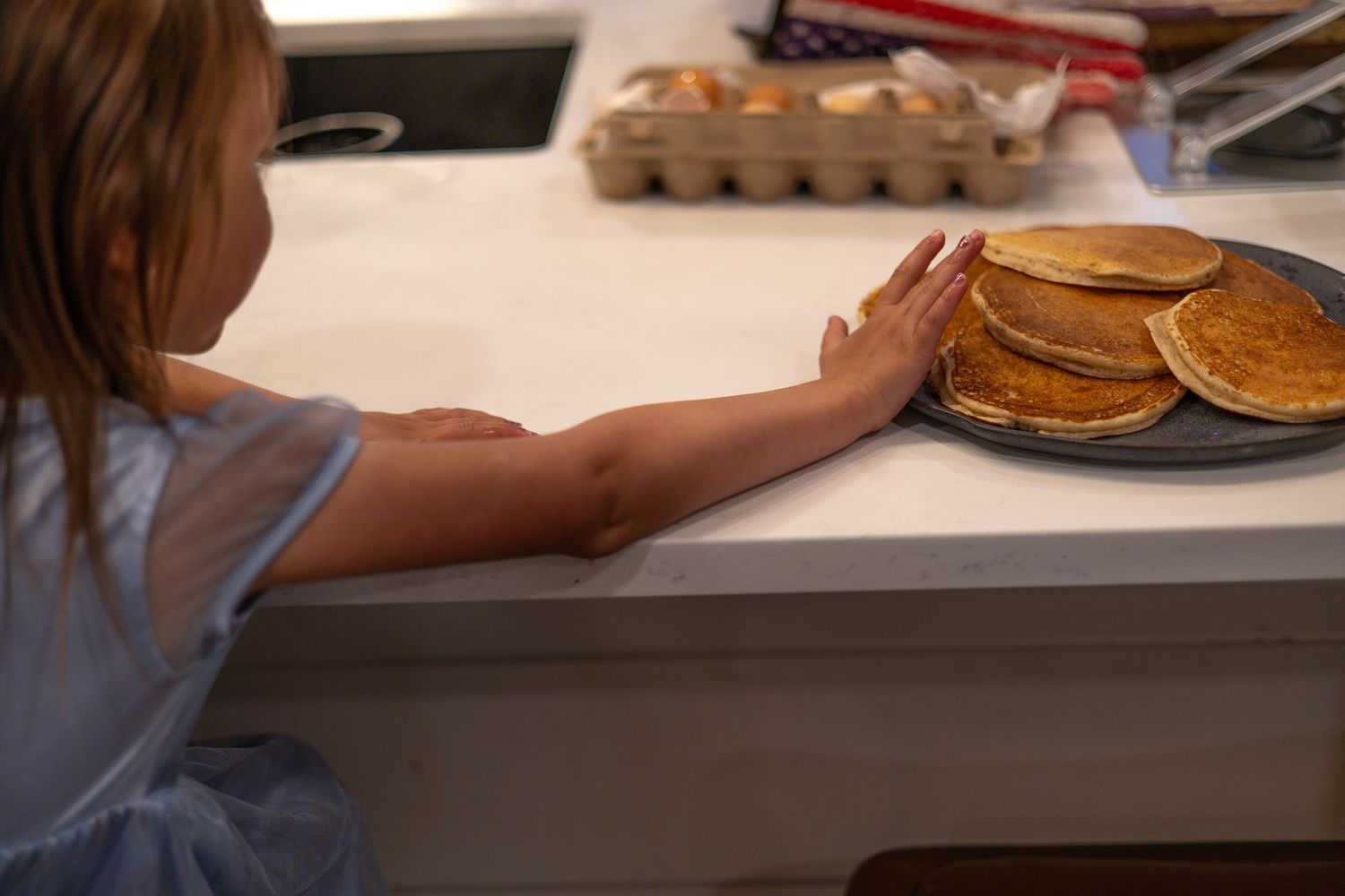 Hands measuring and mixing ingredients for homemade pancakes on a kitchen counter.