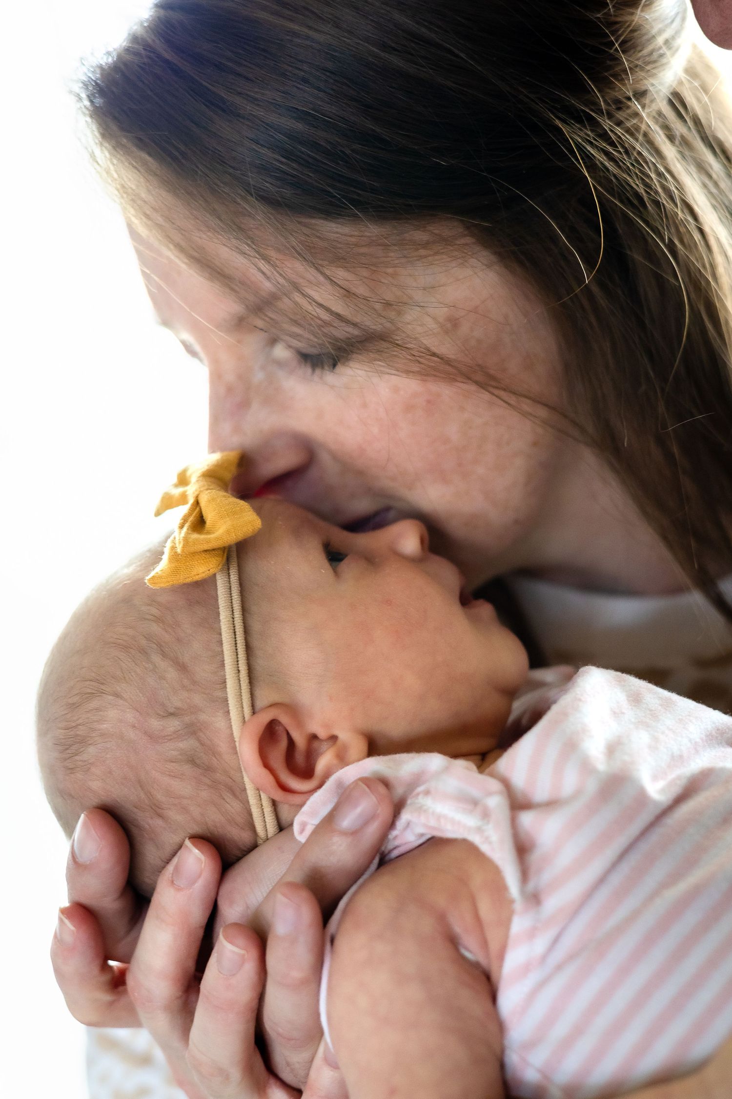 A tender moment of affection between parent and infant in soft lighting.