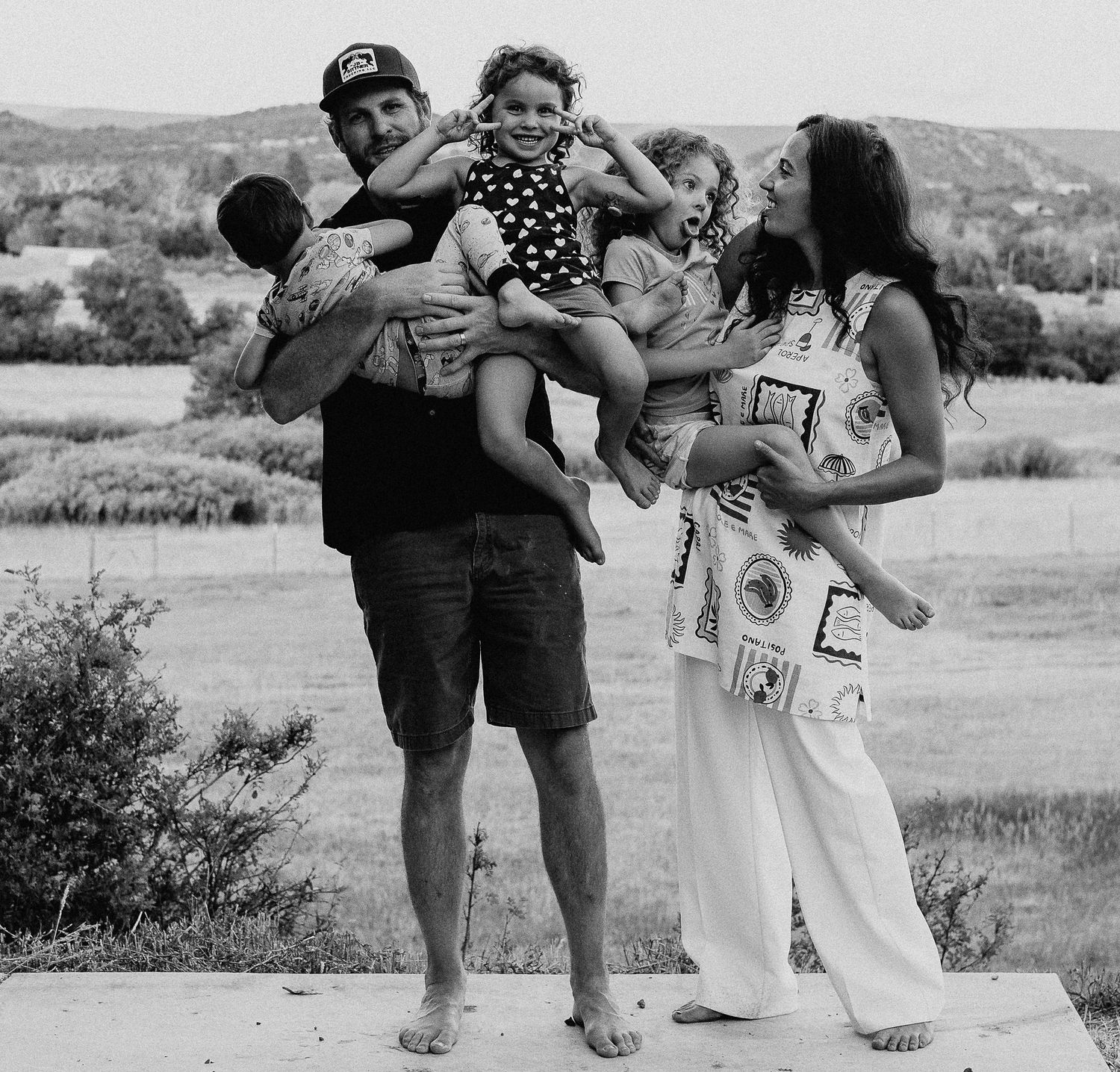 Black and white panoramic collage showing intimate moments between figures in an outdoor setting against rolling hills.
