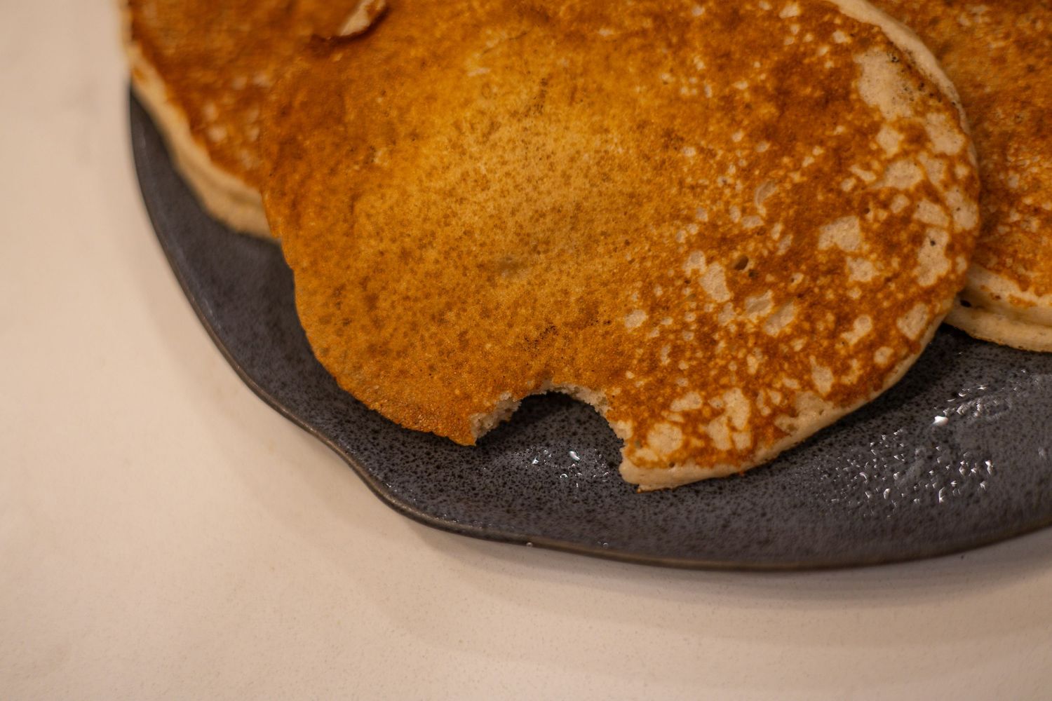 Golden brown pancakes with crispy edges served on a dark gray plate.
