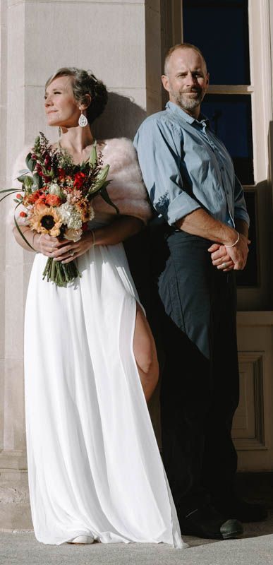 A stylish wedding portrait with the couple posing back-to-back against classic architecture.