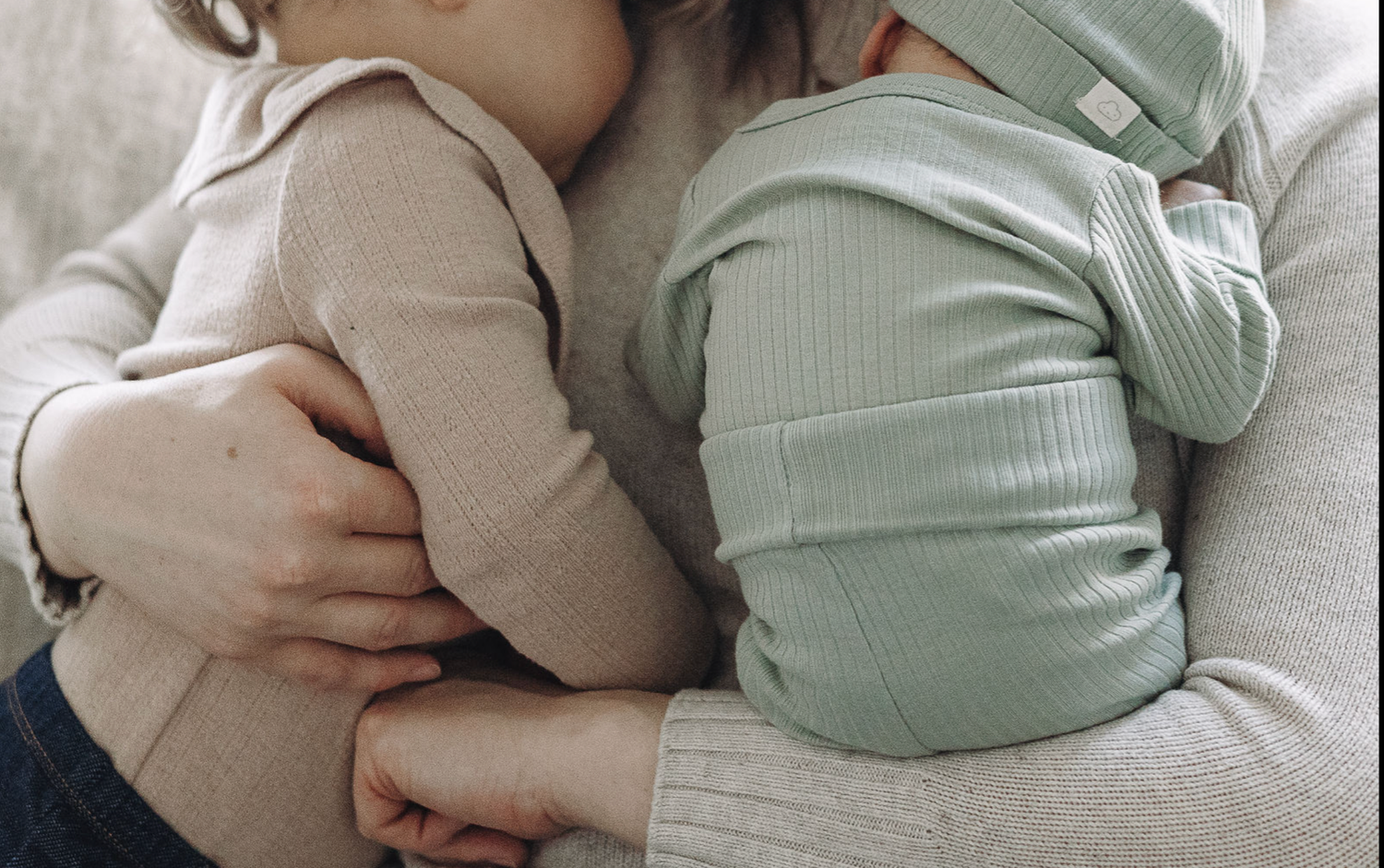 A series of tender moments show someone holding and comforting a newborn baby in white and mint green clothing.