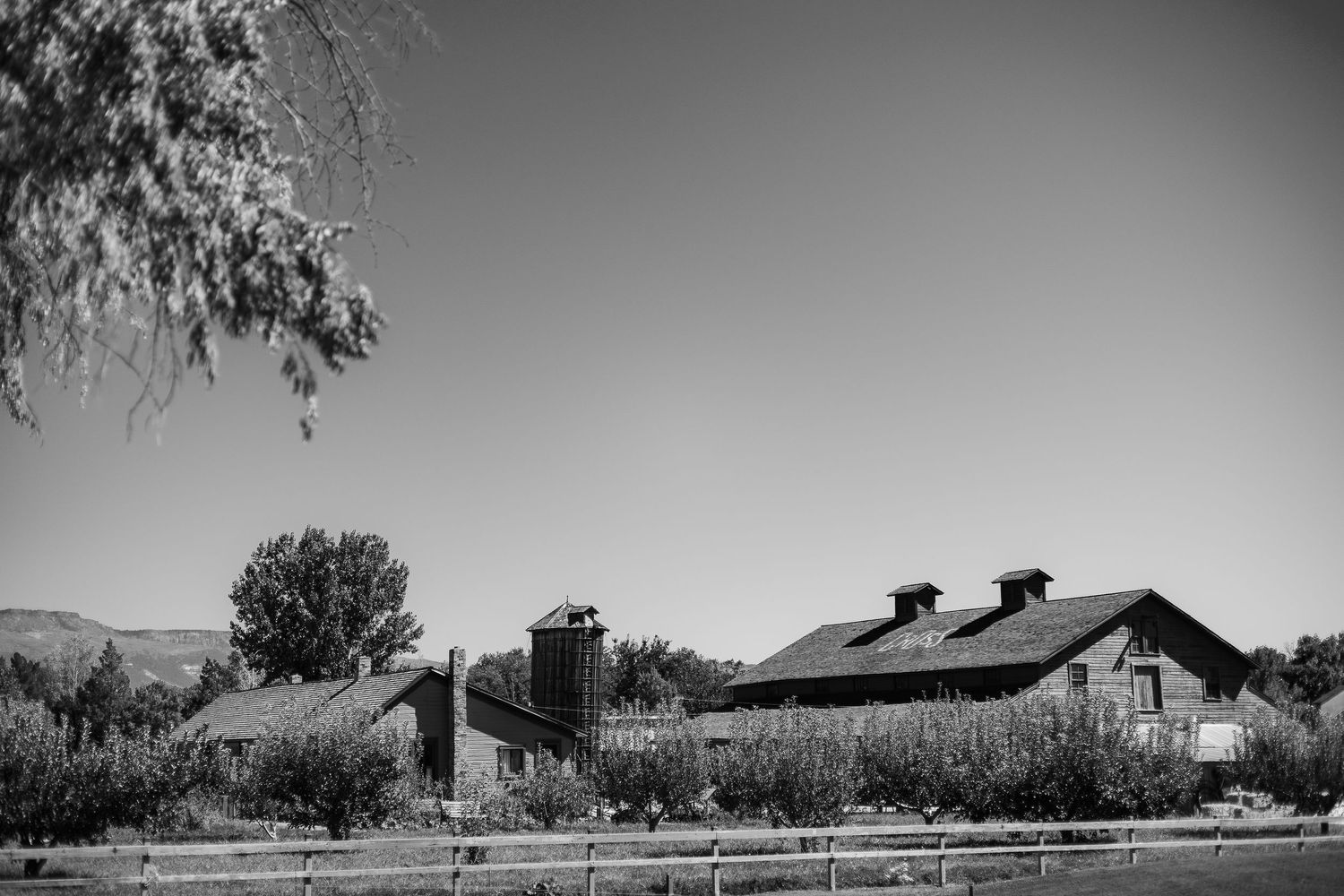 A series of black and white landscape photographs showing rural buildings and desert scenery in panoramic format.