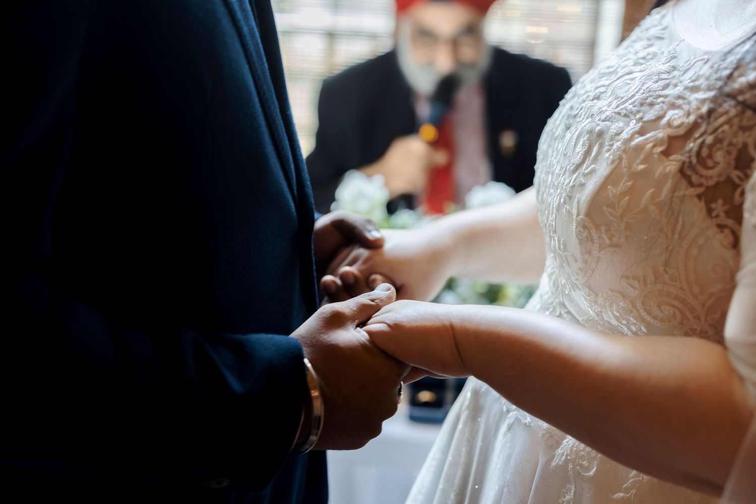 Close-up of bride placing wedding ring on groom's hand during an intimate ceremony exchange.