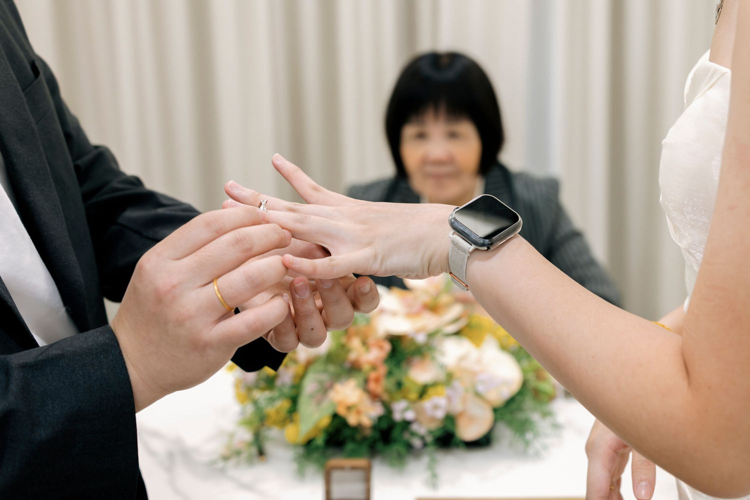 Close-up of groom placing wedding ring on bride's finger during civil solemnization ceremony.
