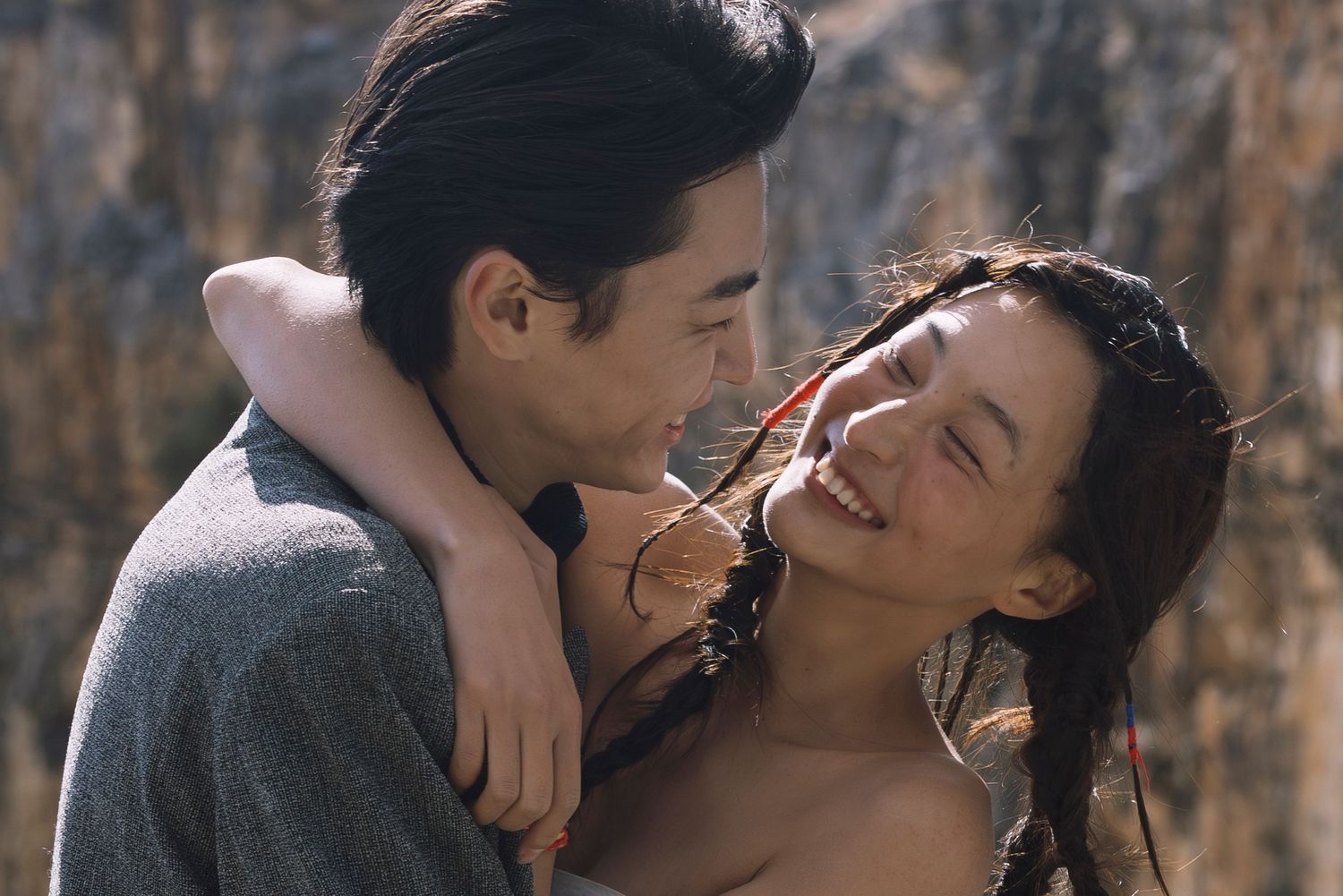 Happy couple embracing and laughing together outdoors in a joyful and intimate romantic moment.
