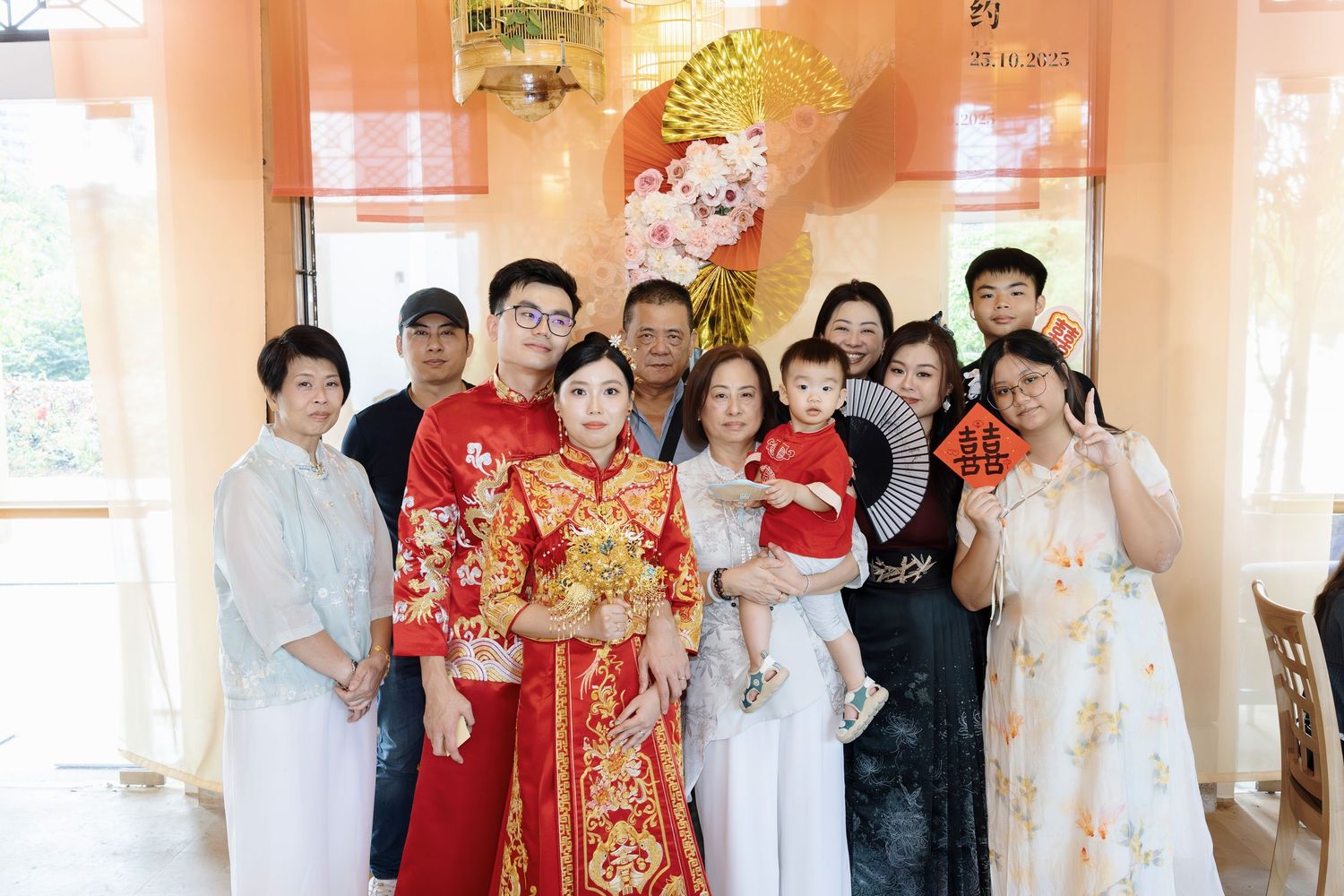 Family group photo at a traditional Chinese wedding celebration with bride in red qipao dress.