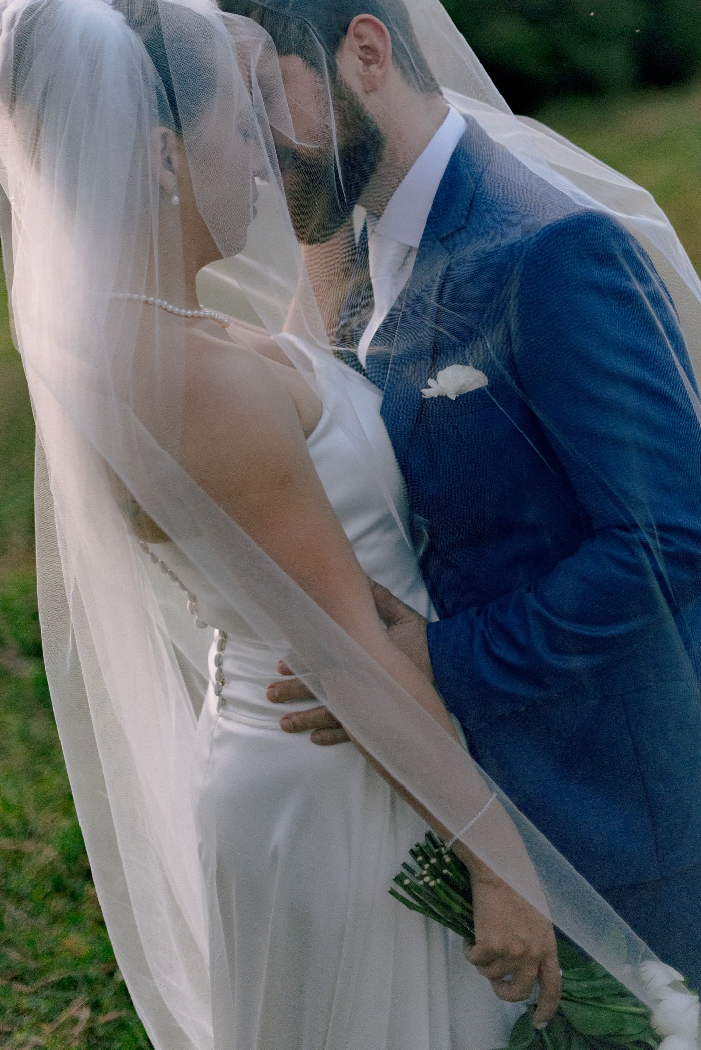 A romantic wedding moment with the couple sharing a kiss under a flowing white veil.