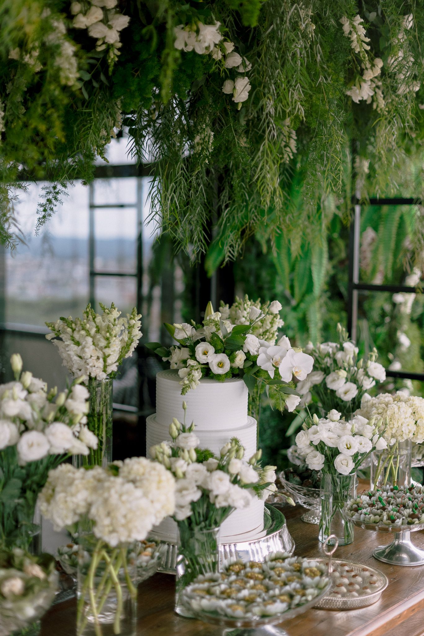 Wedding reception decor featuring lush greenery and white floral arrangements.