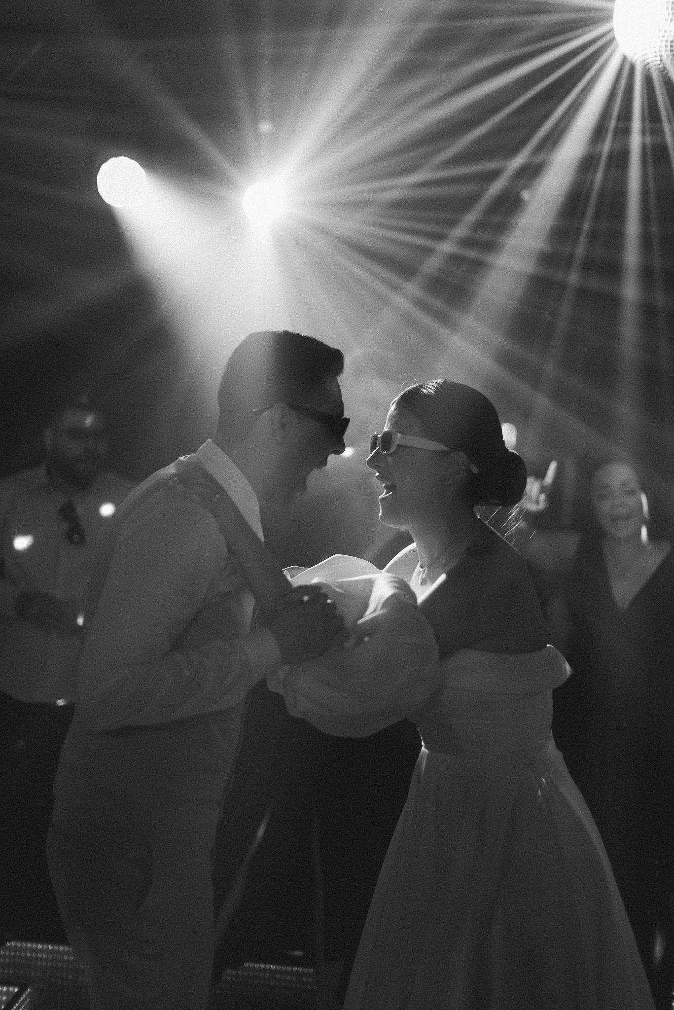 Silhouetted wedding party dancing under dramatic starburst lighting effects.