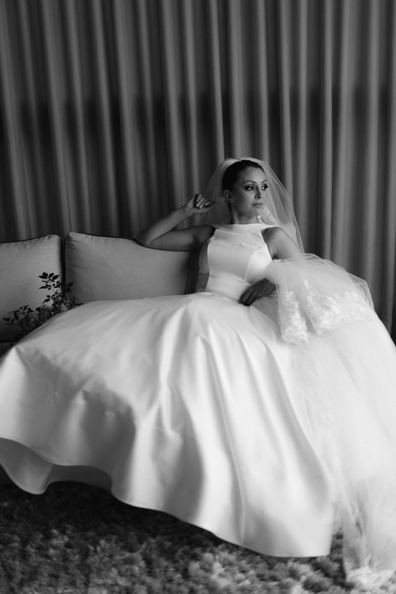 Artistic black and white portrait of a wedding dress draped across furniture.
