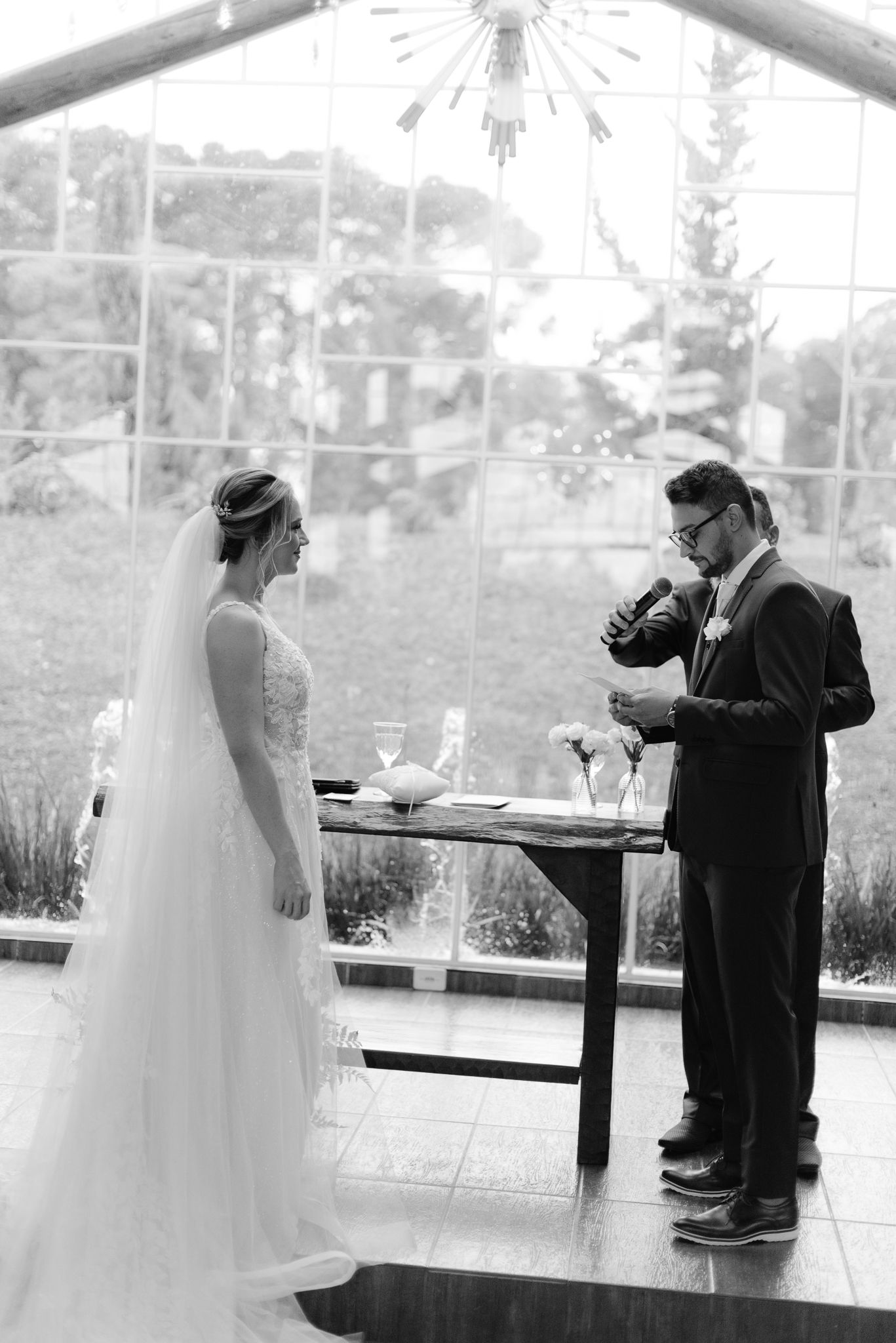 Black and white photo of a wedding ceremony with couple standing at altar table.