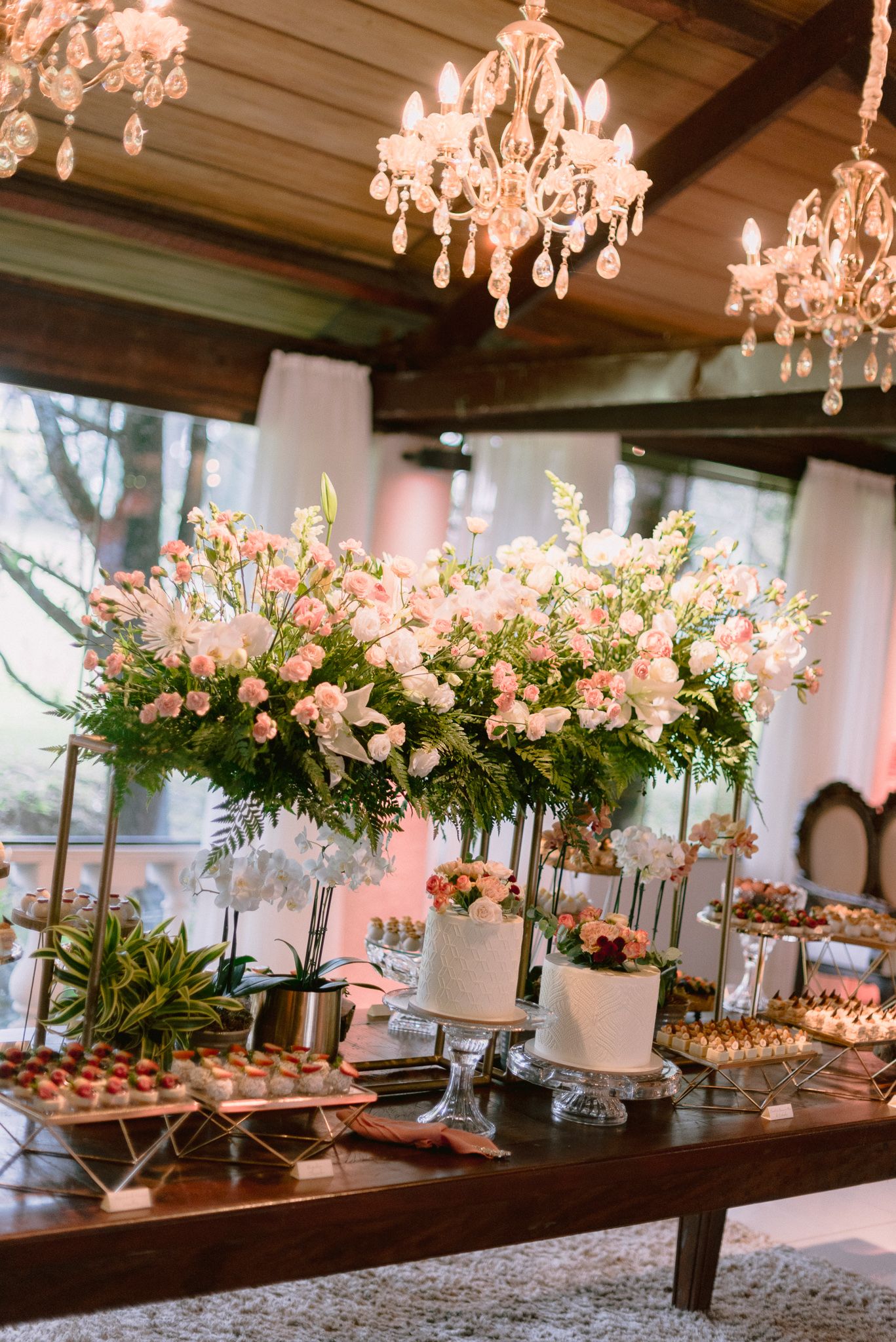 Stunning dessert table display with floral arrangements and chandeliers at an elegant wedding reception.