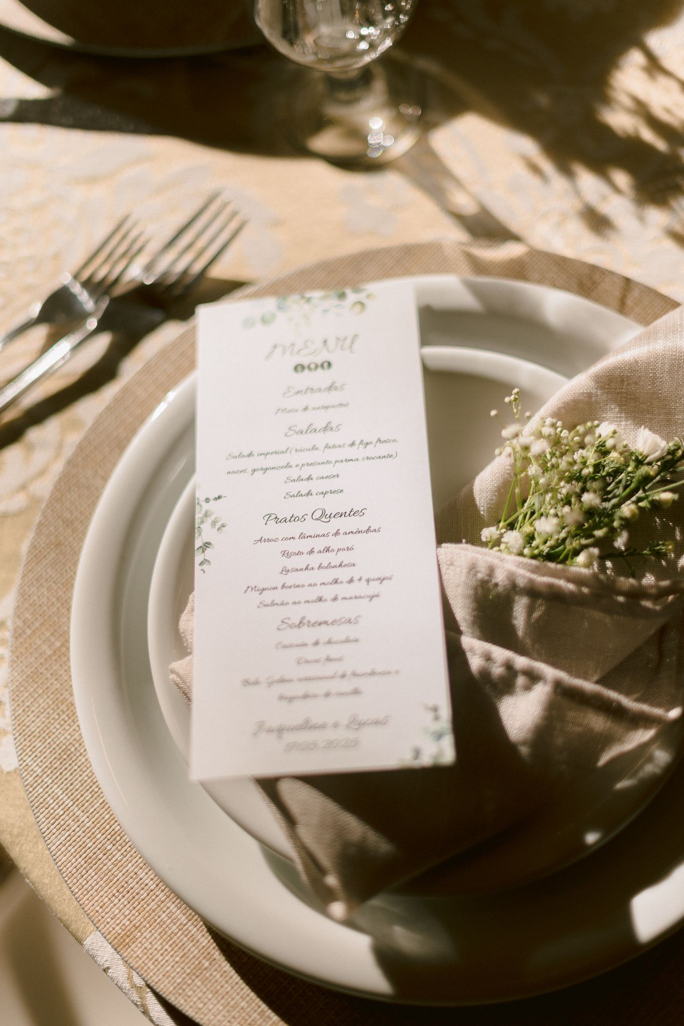 Elegant wedding reception place settings with white plates, burlap placemats and menu cards at each seat.