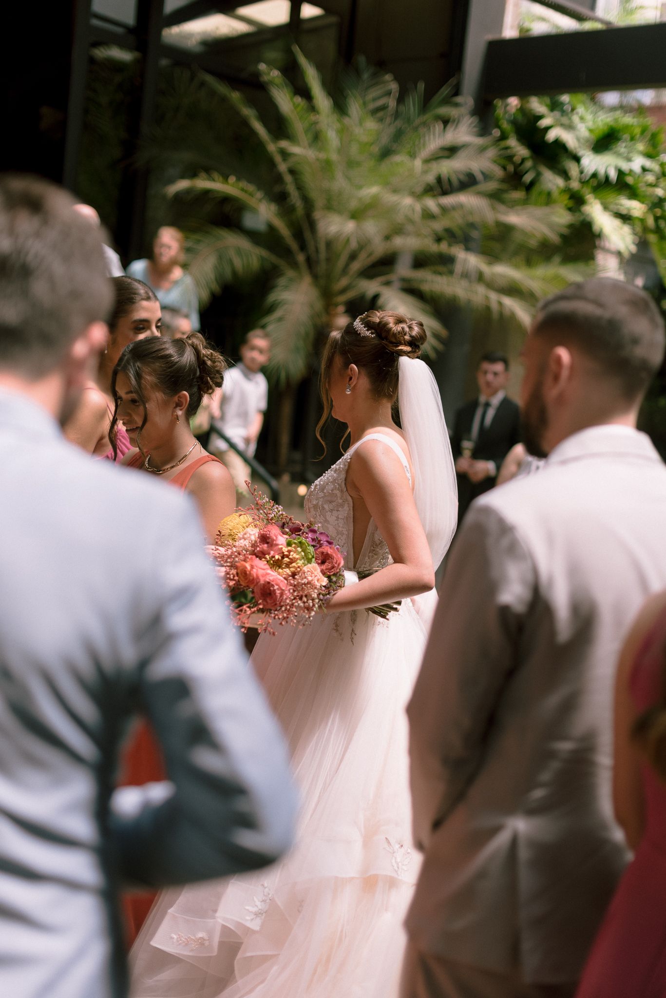 A wedding ceremony in progress with guests watching as a bride in white dress walks down the aisle.