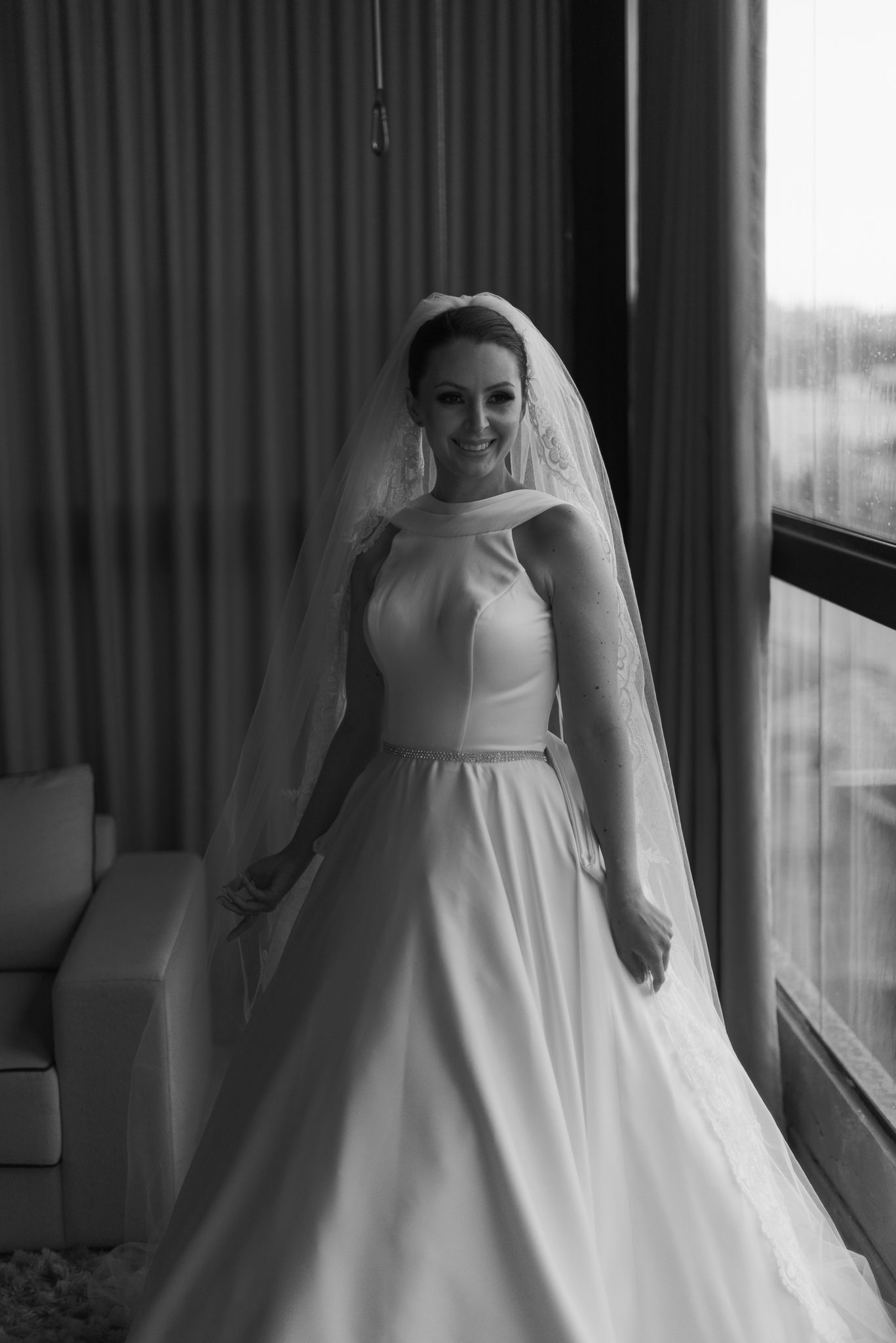 Classic bridal portrait showcasing full ballgown and veil near window.