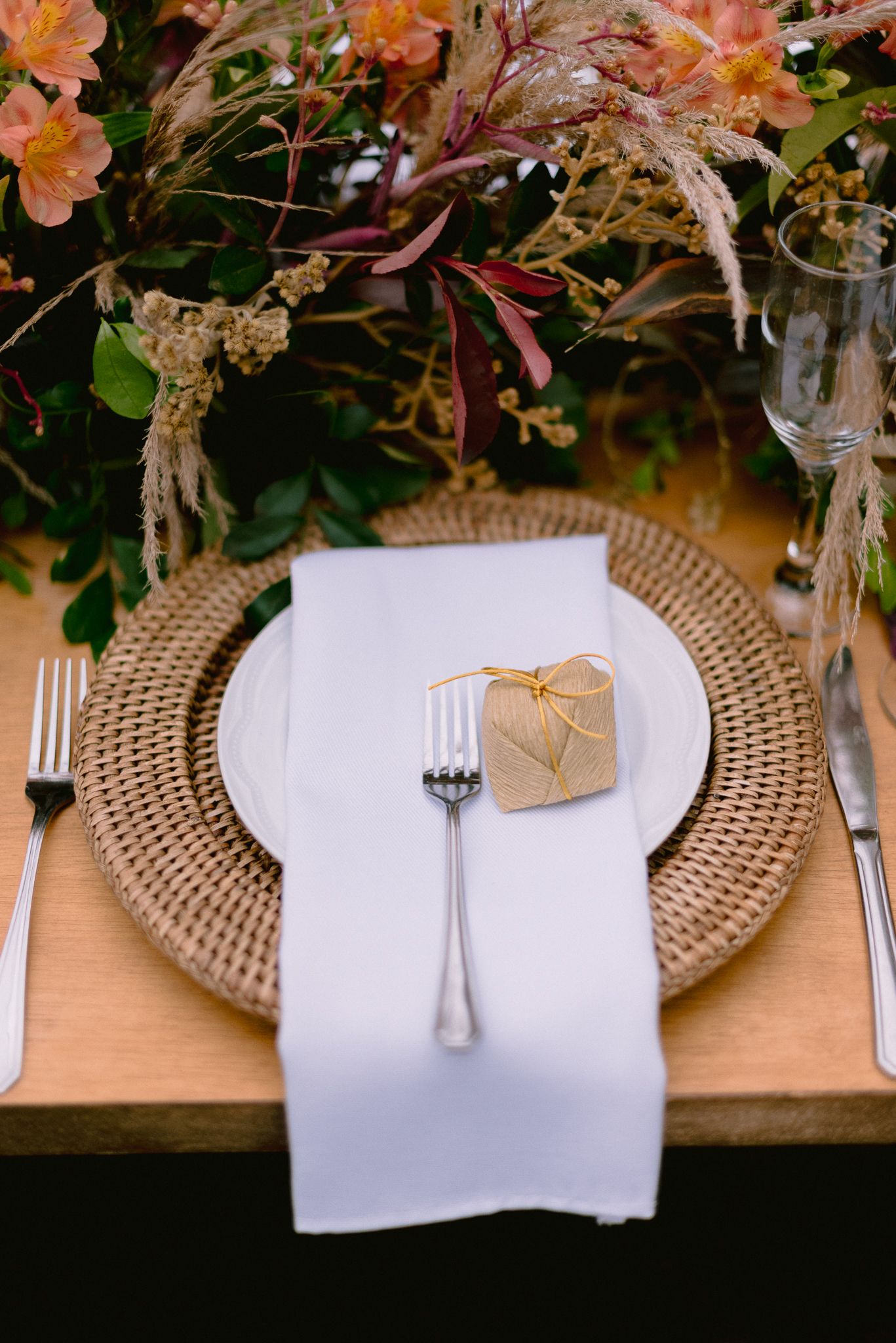 Elegant place setting with gold charger plates and coral floral centerpieces.