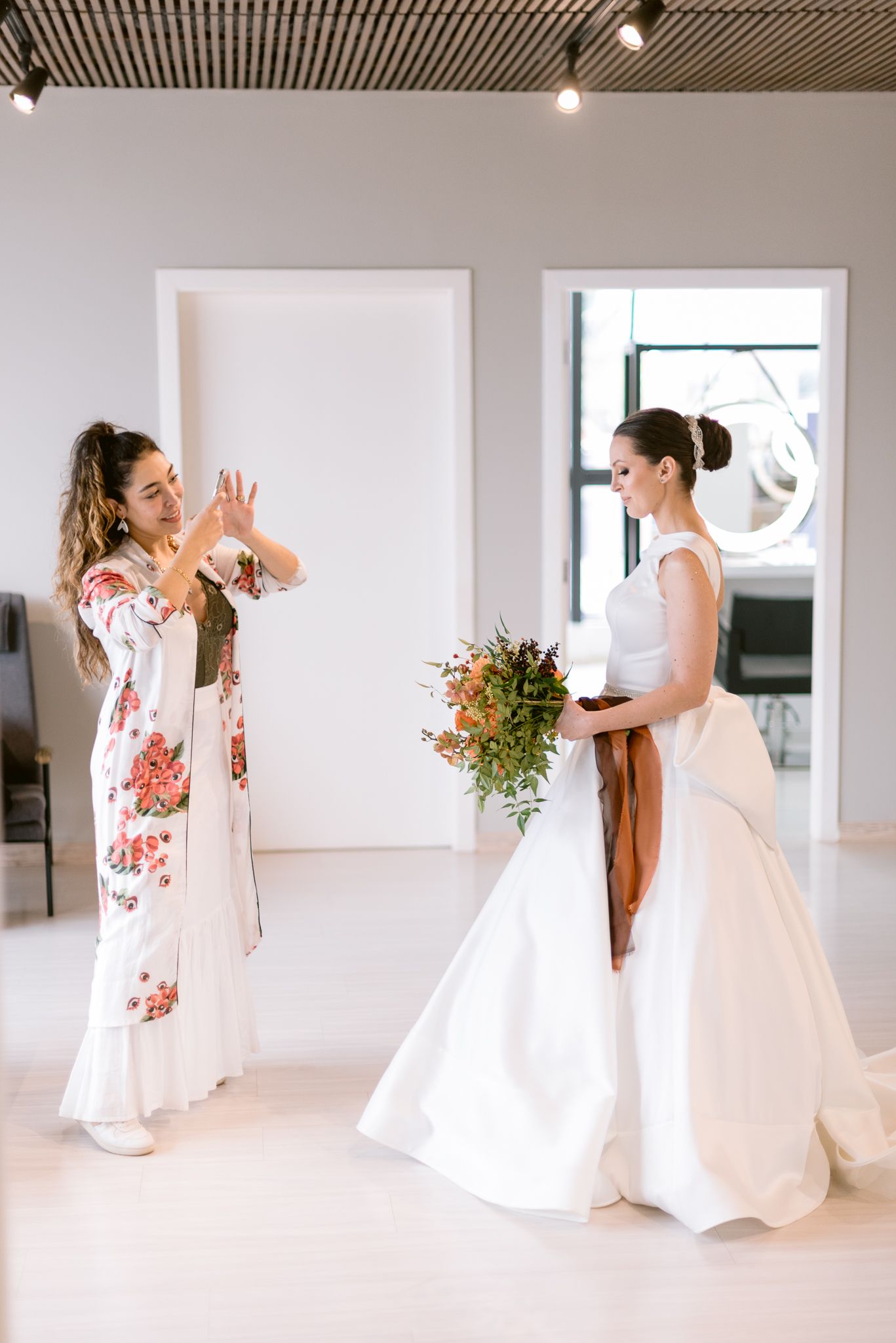 Bright white room with multiple windows showing dance and movement in wedding attire.
