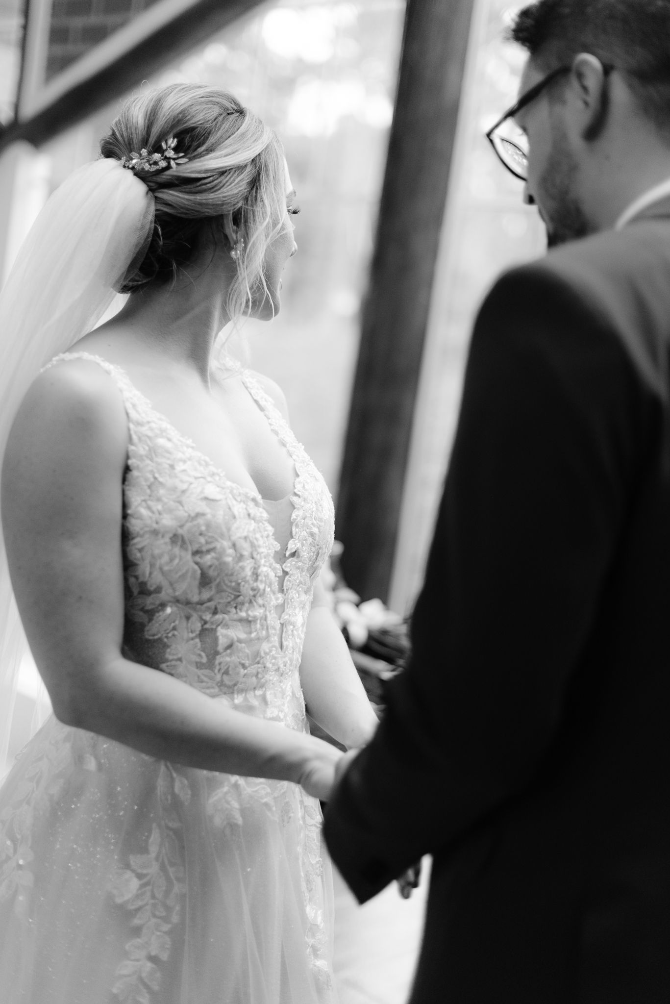 Close-up side view of bride and groom during wedding ceremony showing lace dress detail.