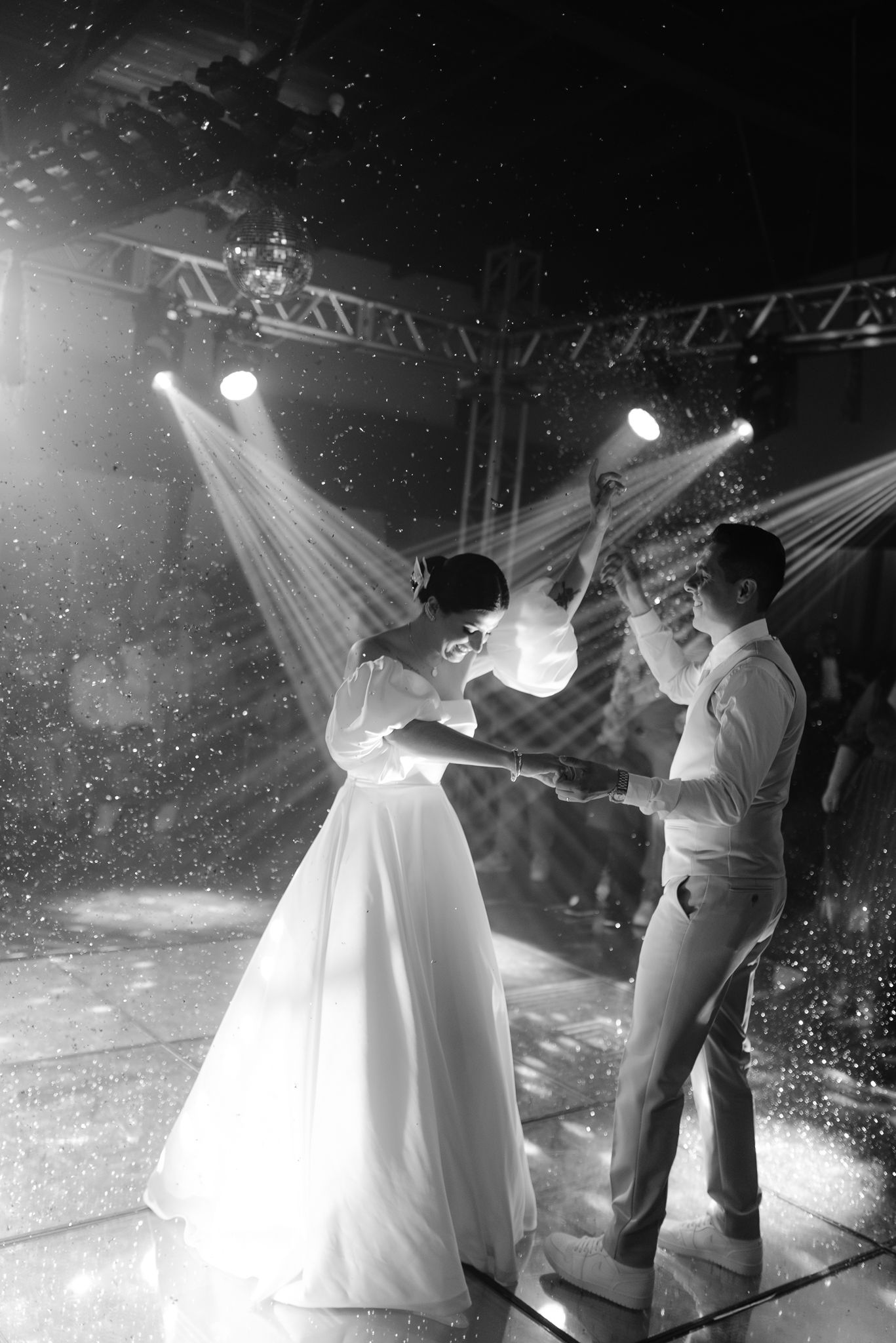 Couple sharing their first dance under dramatic spotlights at their wedding reception.