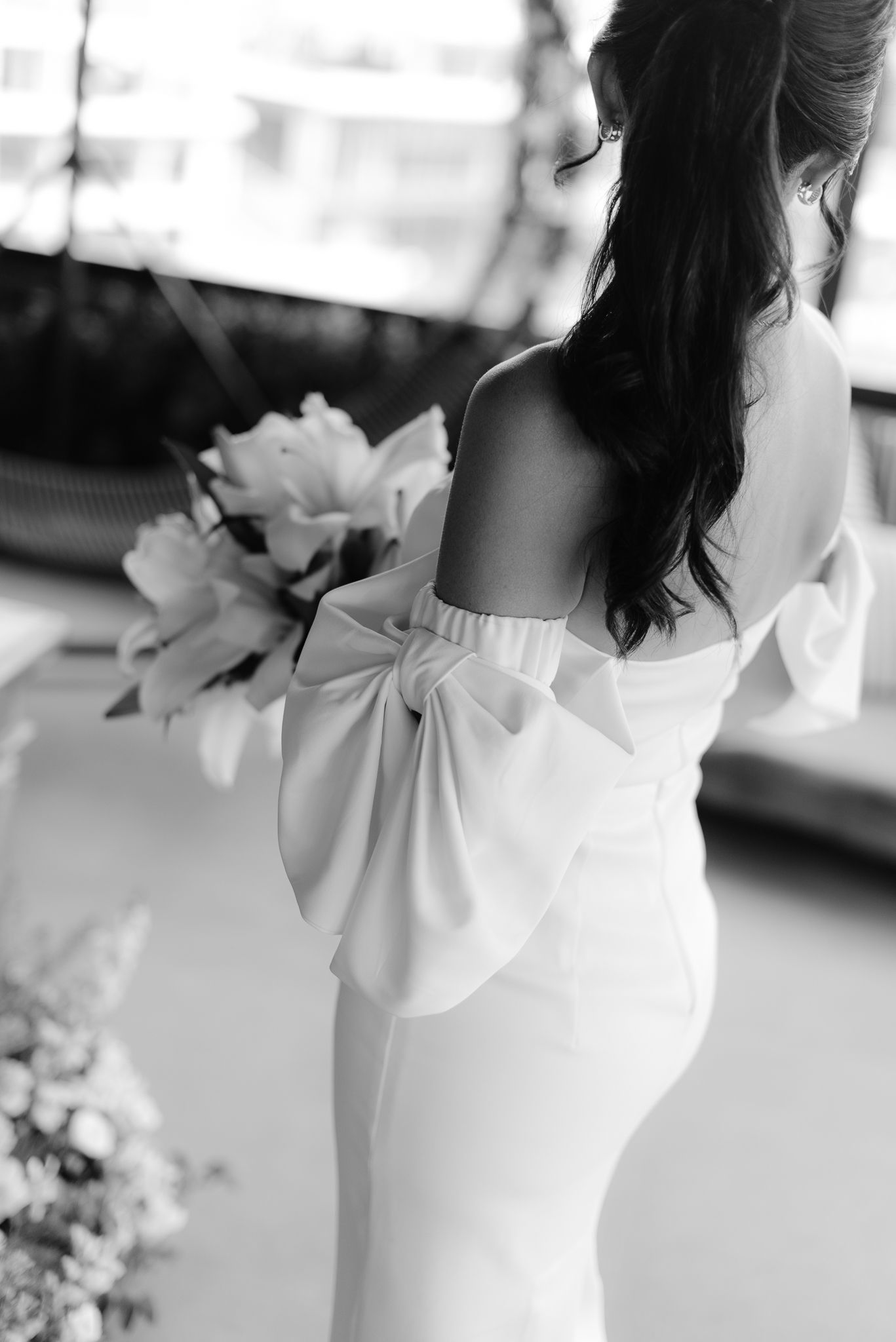 Close-up details of a white wedding dress with a bow design on the back.