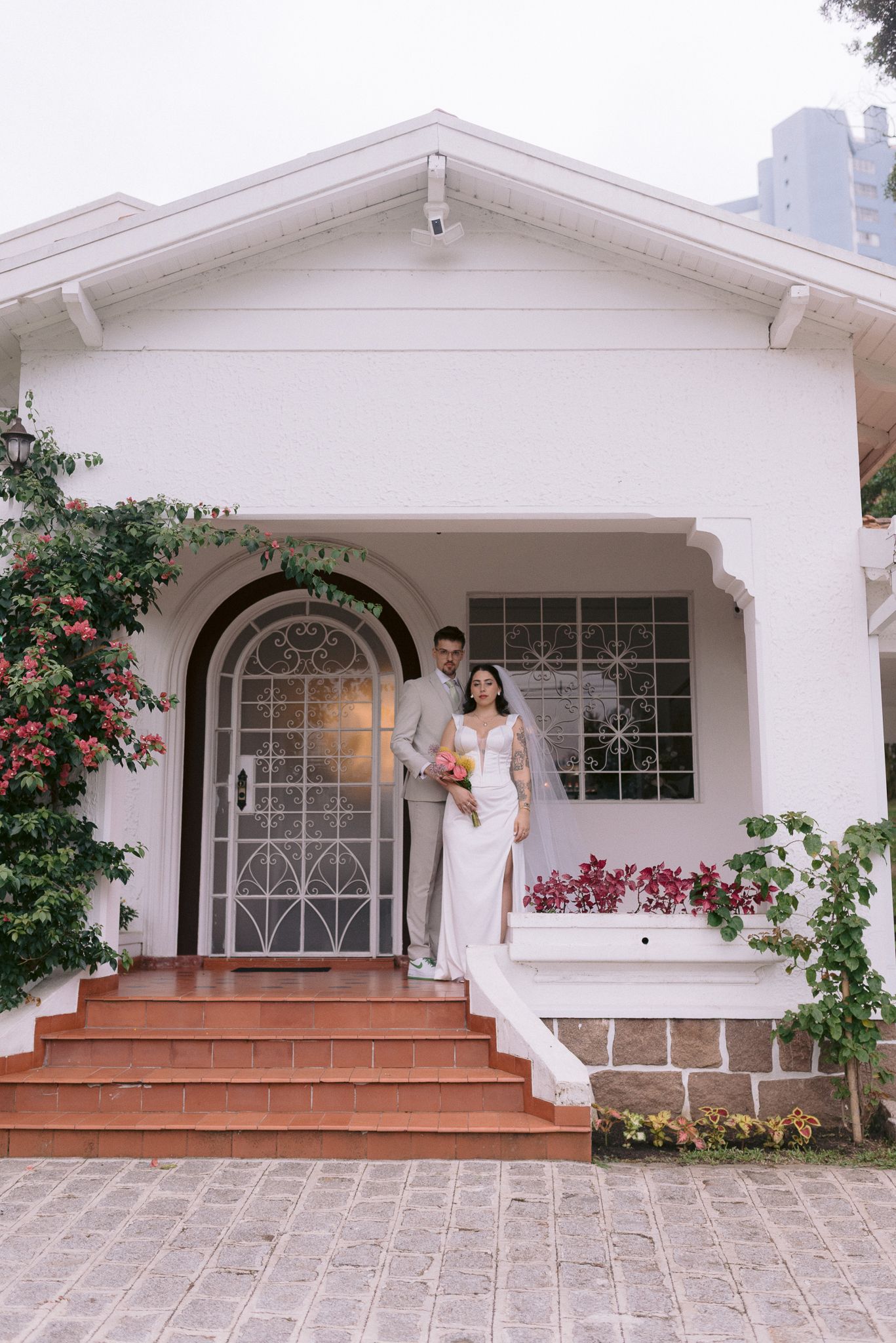 White stucco house exterior with arched doorway and terra cotta steps decorated for a wedding.