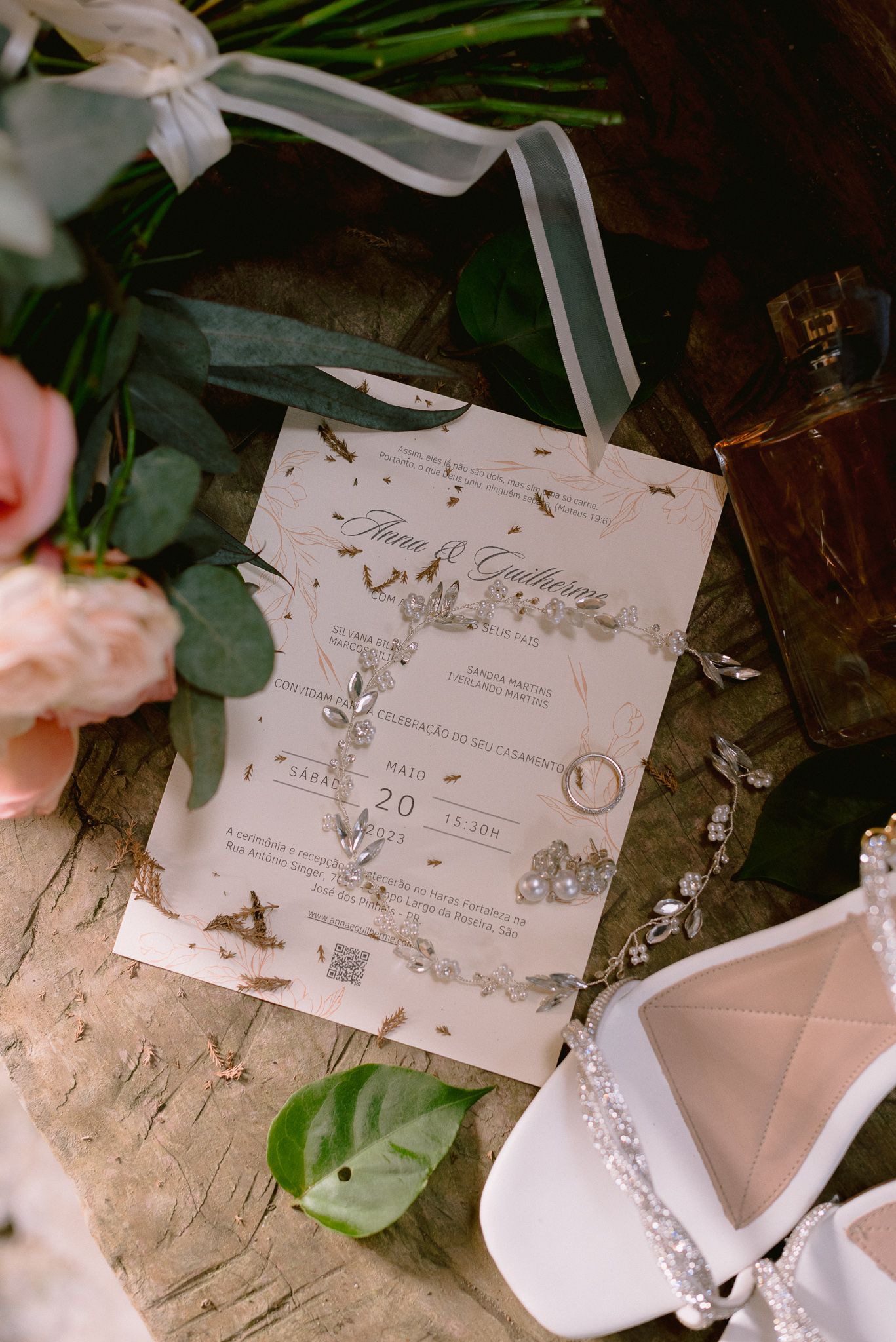 Wedding invitation suite with delicate floral designs laid out among greenery and ribbons.