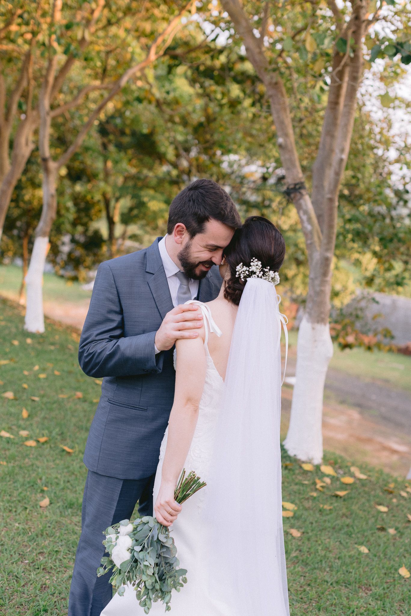 A tender moment between newlyweds in a garden setting with autumn trees.
