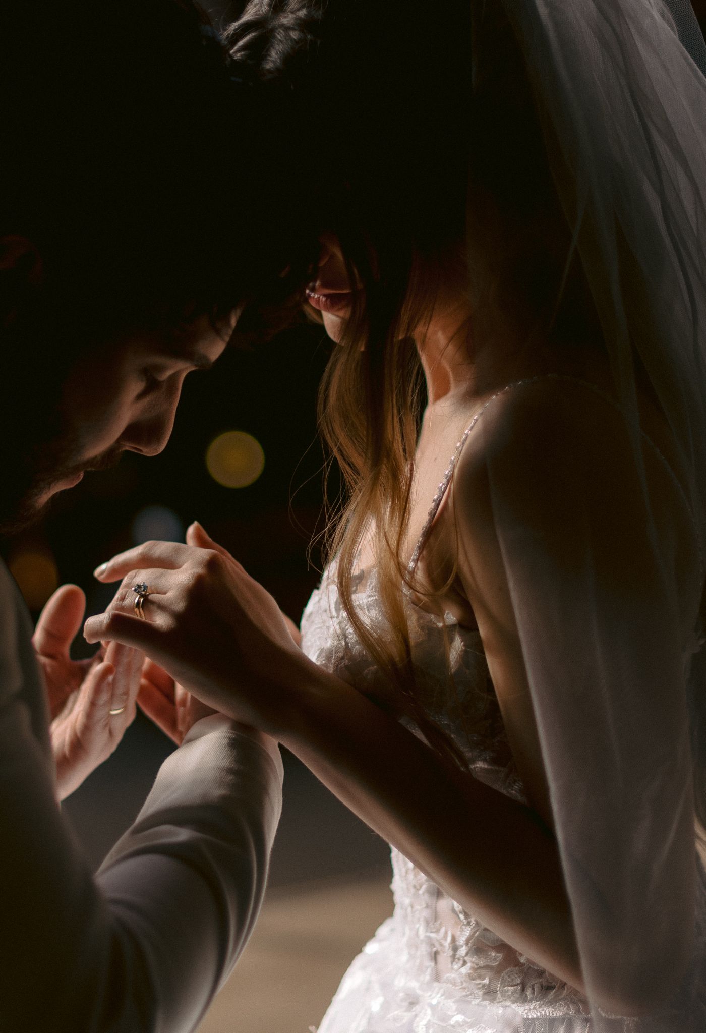 Silhouette of a bride getting into her wedding dress in dramatic moody lighting.