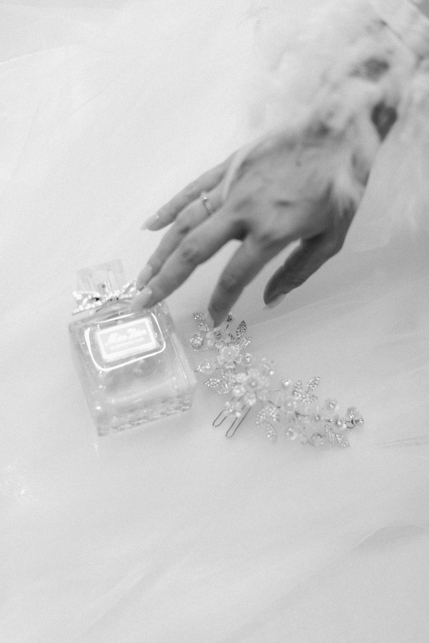 A hand arranges delicate silver and crystal snowflake decorations on a white surface.