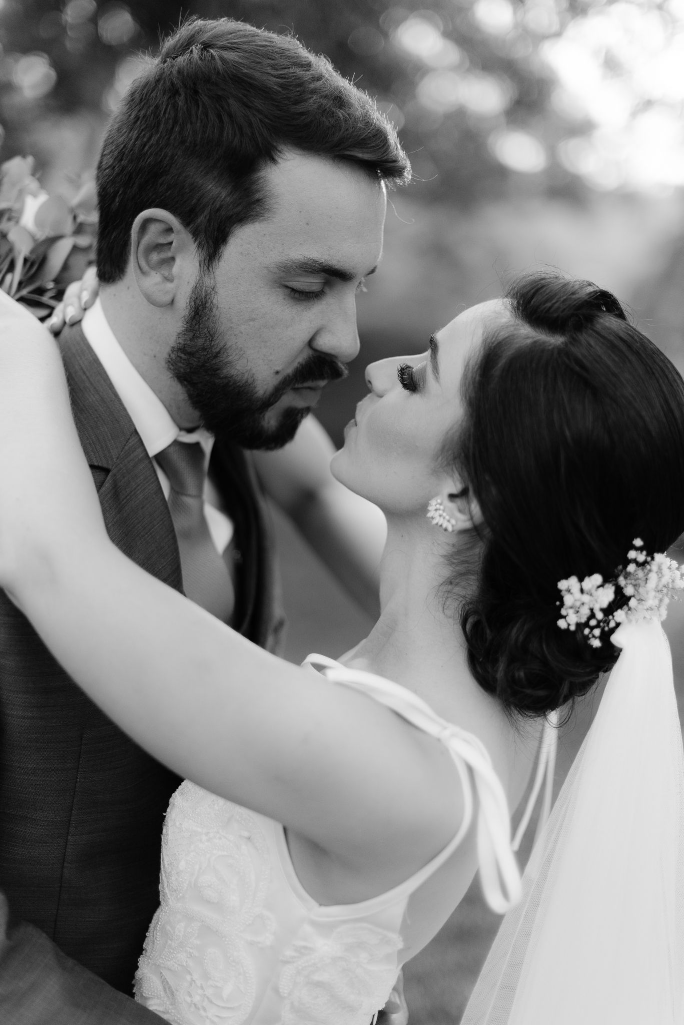 A romantic black and white wedding portrait of a couple sharing an intimate moment.