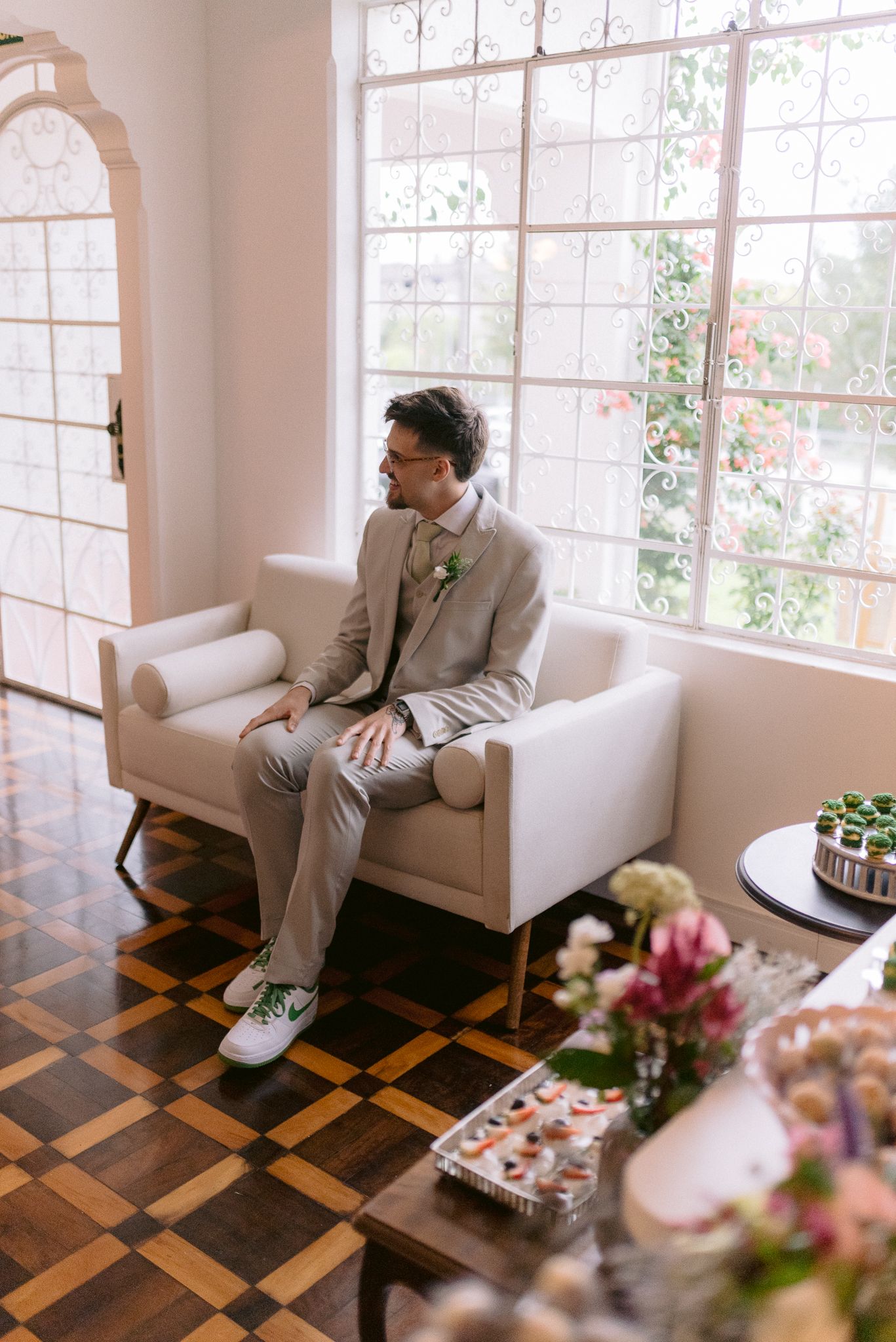 Light-filled room with geometric floor pattern and white couch adorned with pink flowers.