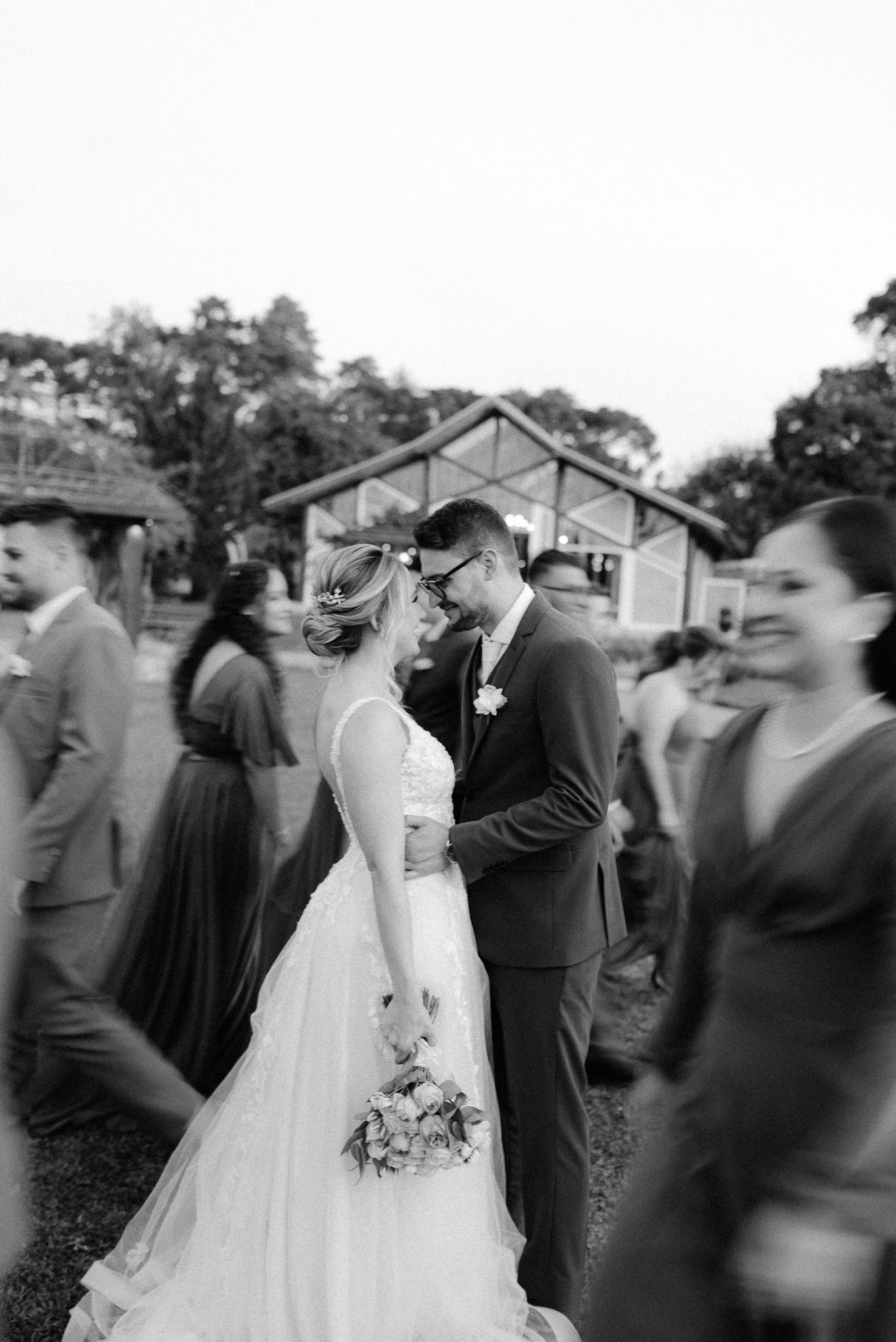 A black and white wedding photo showing guests surrounding the couple during their celebration.
