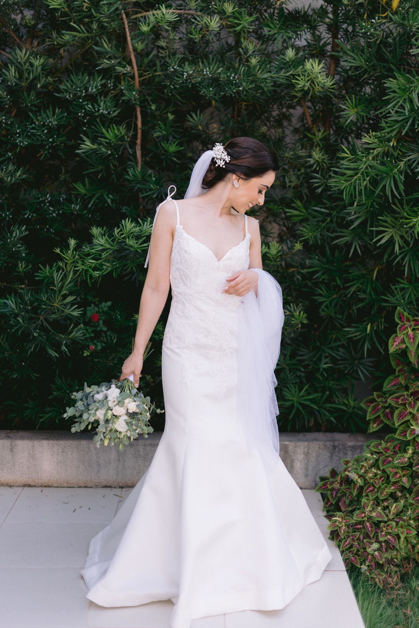 White wedding dress flowing in movement against green garden backdrop.