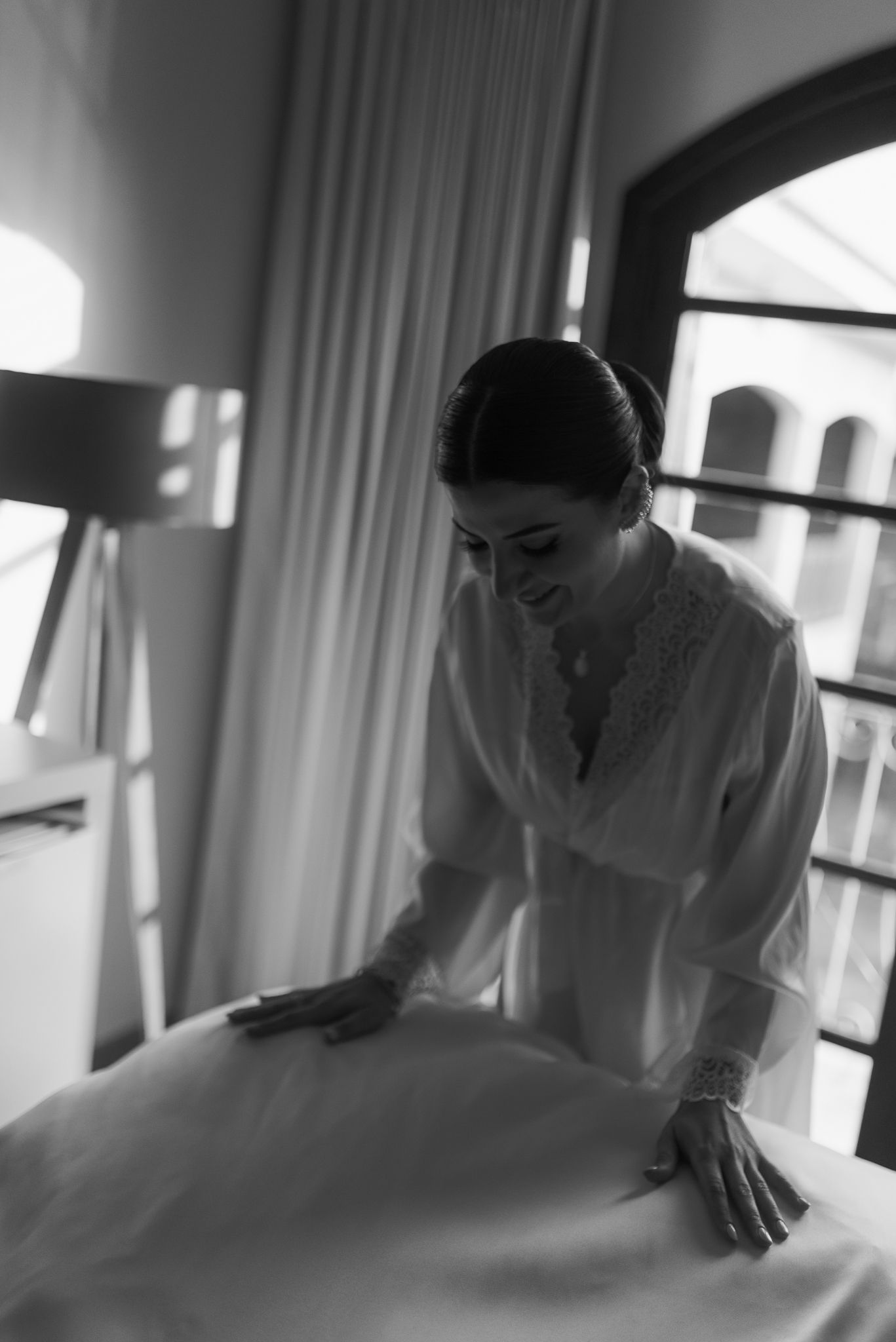 Black and white photo of wedding dress preparations in a sunlit room.
