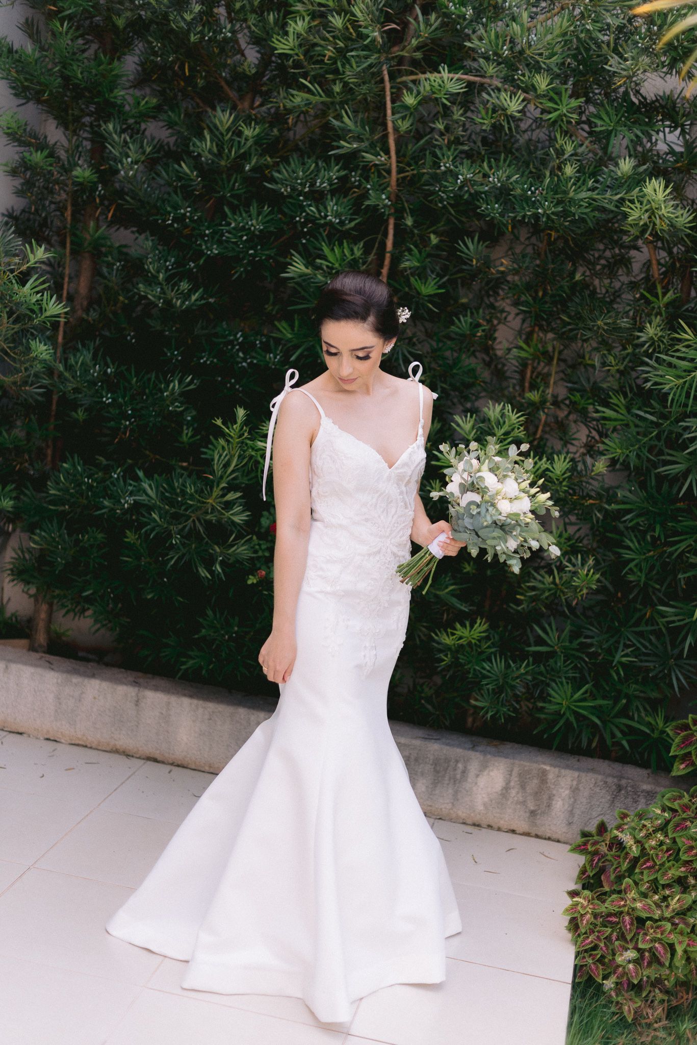 Elegant bridal portraits in a white dress against a backdrop of green foliage.