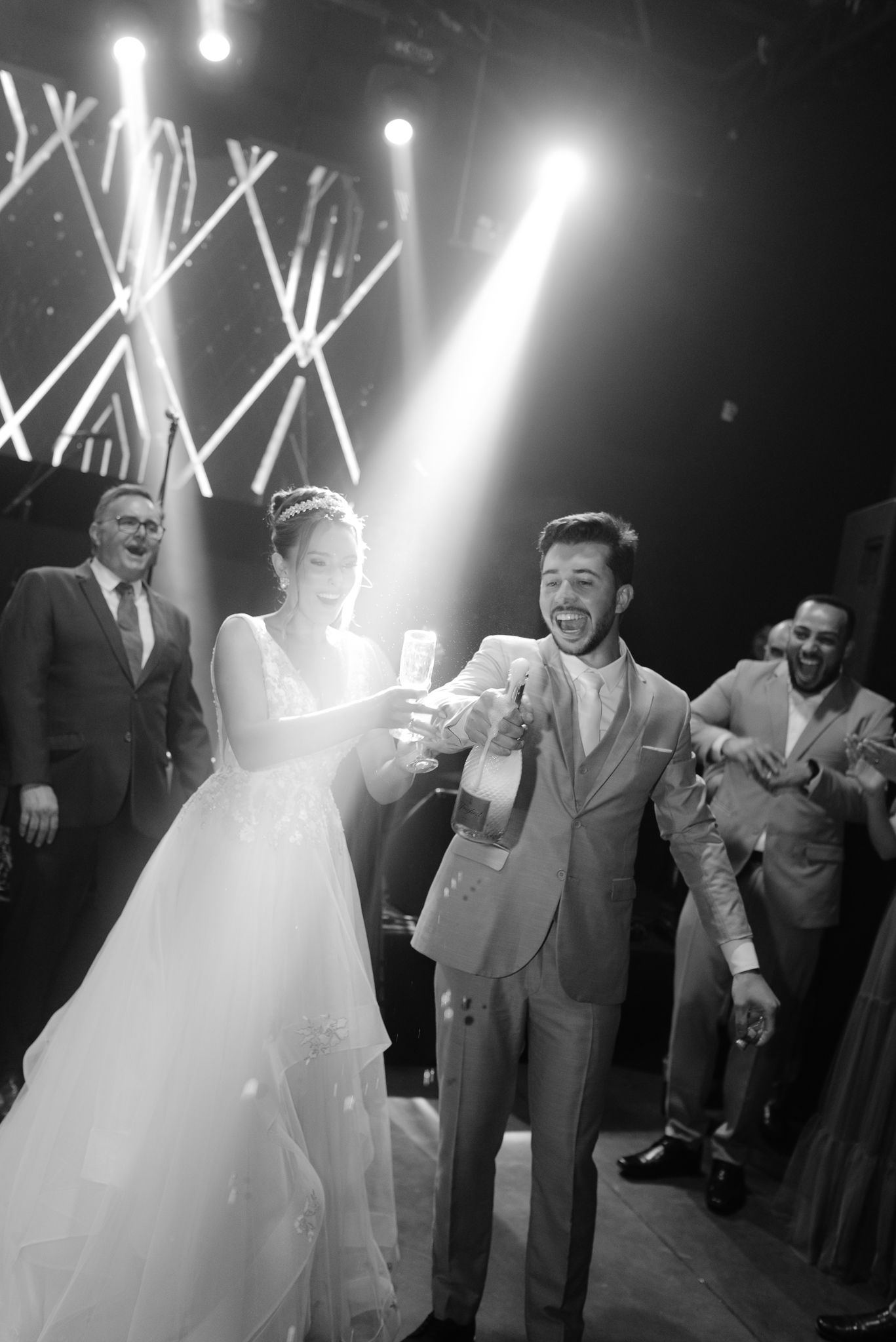 Black and white photos show joyful wedding reception dancing with guests in formal attire under dramatic lighting.