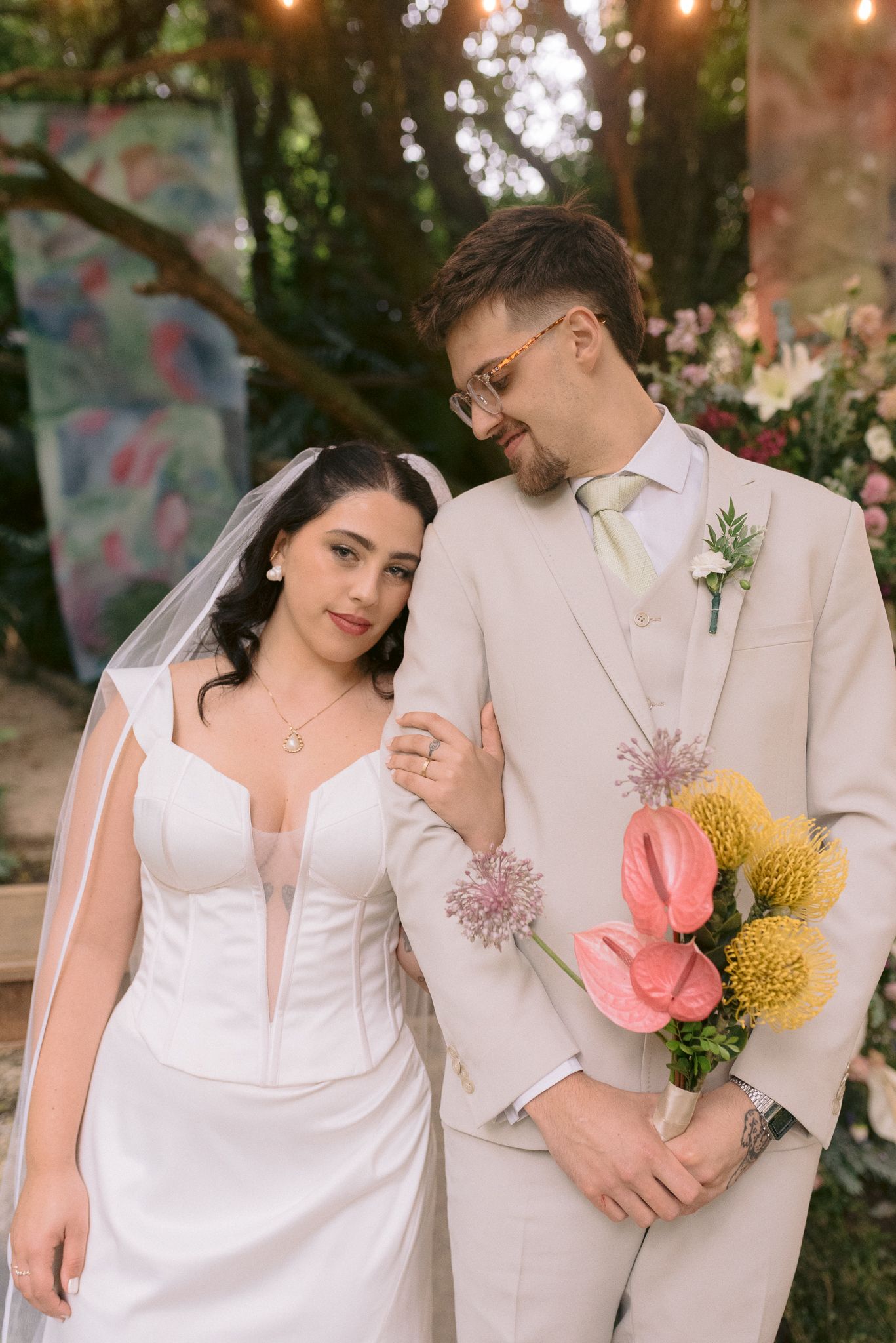 Romantic garden wedding portraits with couple in white attire holding colorful bouquet.