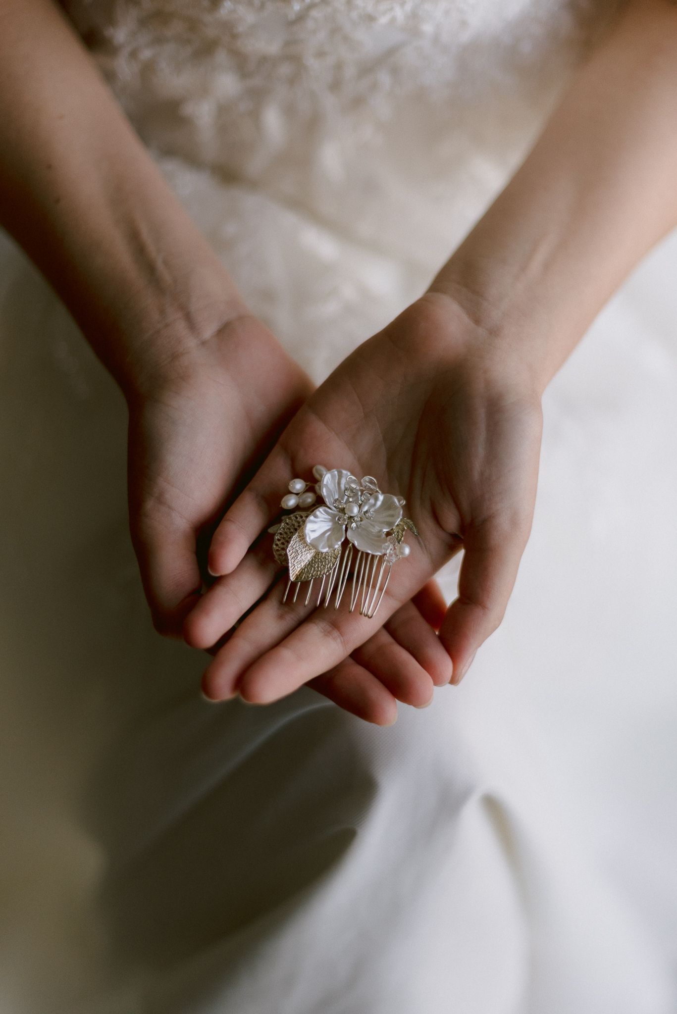 A series of delicate detail shots showing hands holding vintage-style bridal accessories and rings against white fabric.