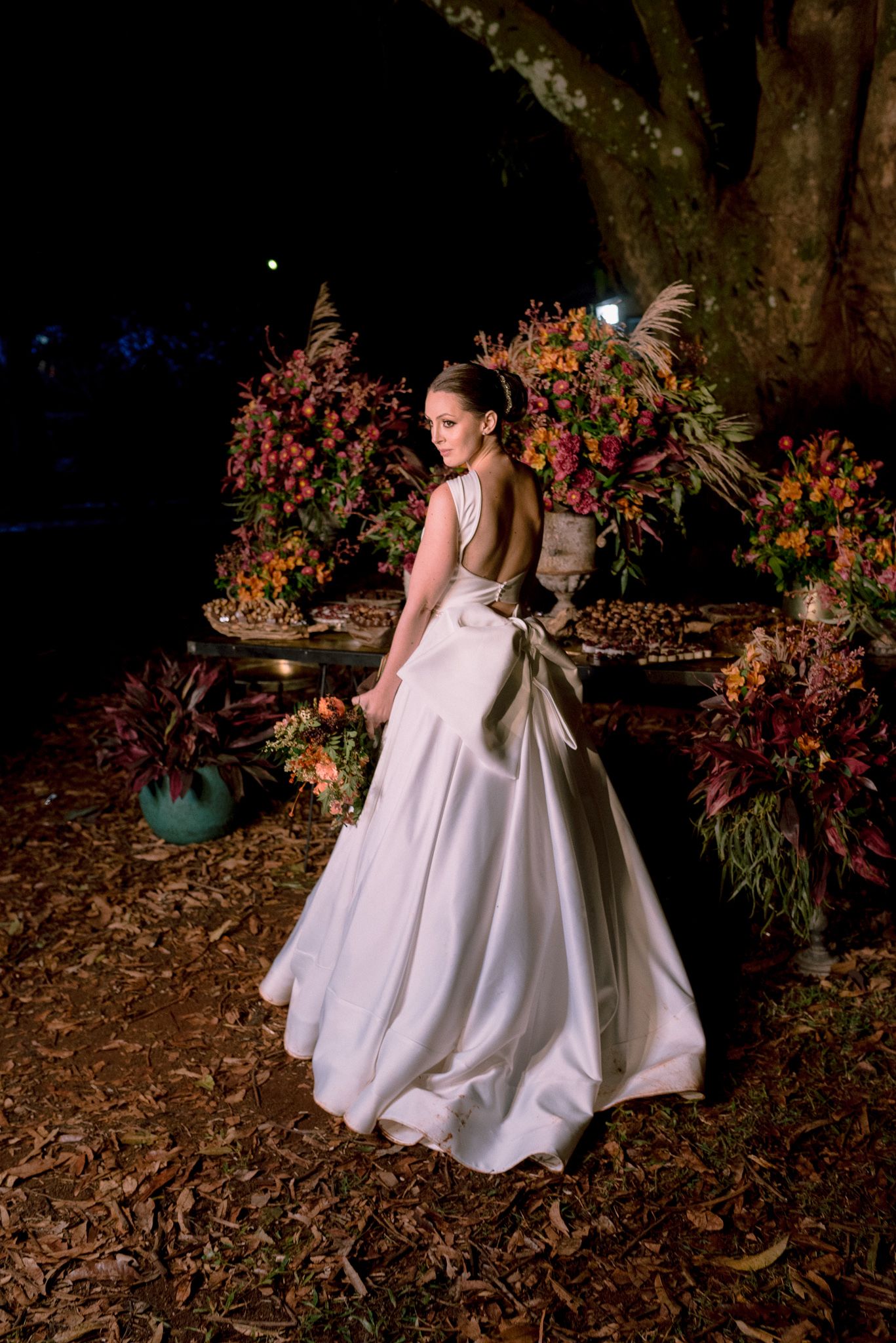 Wedding couple posing in an outdoor garden setting with dramatic evening lighting.