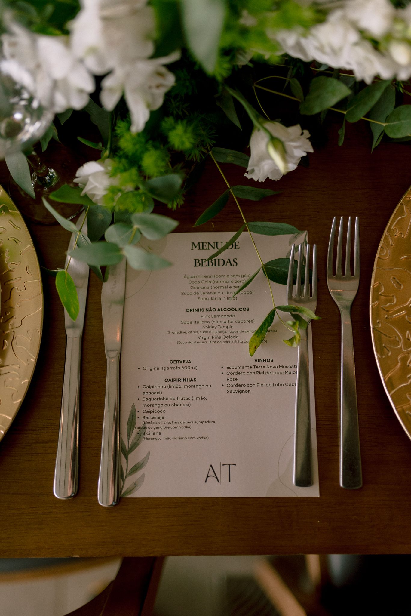 Wedding menu card with greenery and gold charger plate place setting.