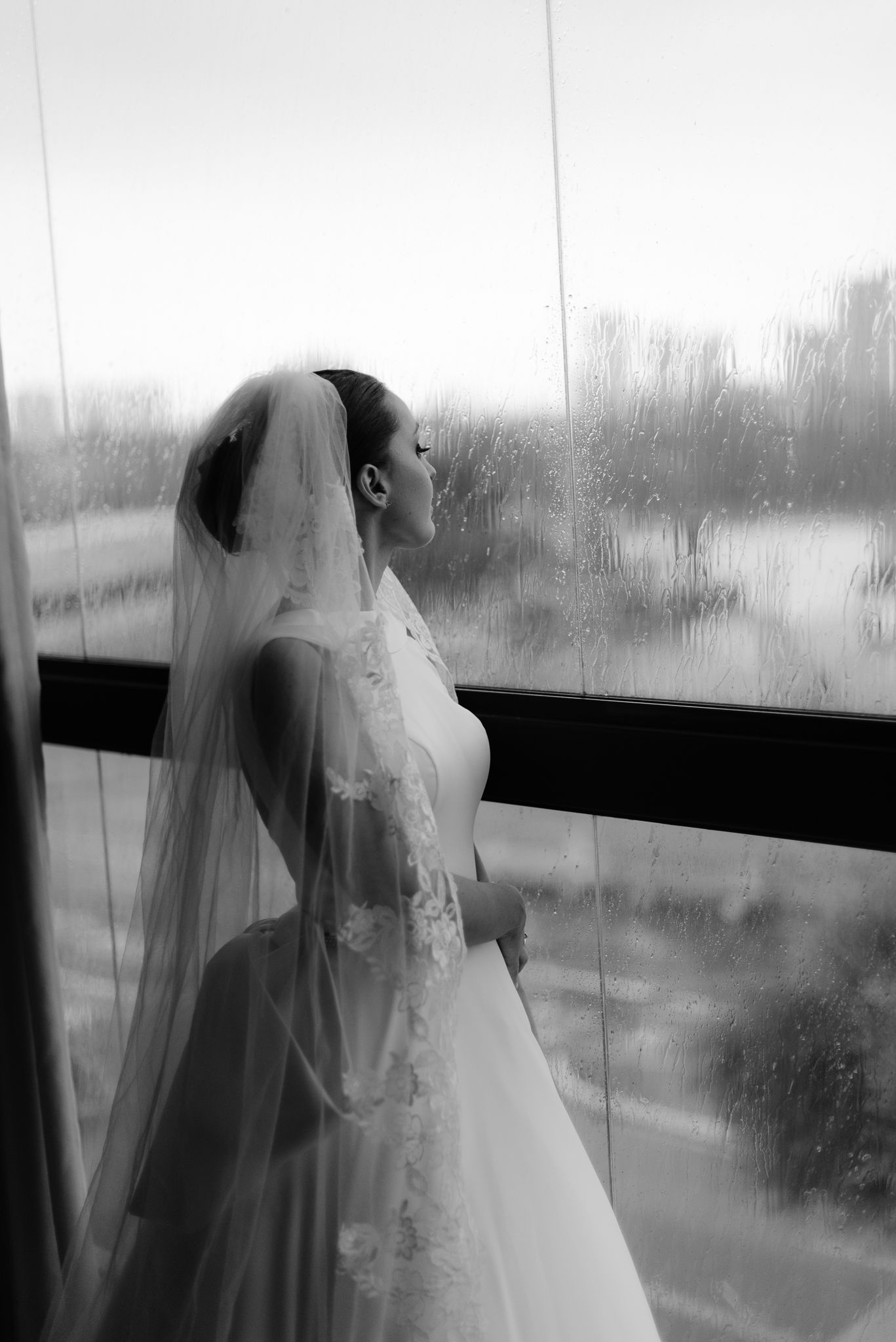 Artistic black and white shot of wedding dress silhouette against window light.