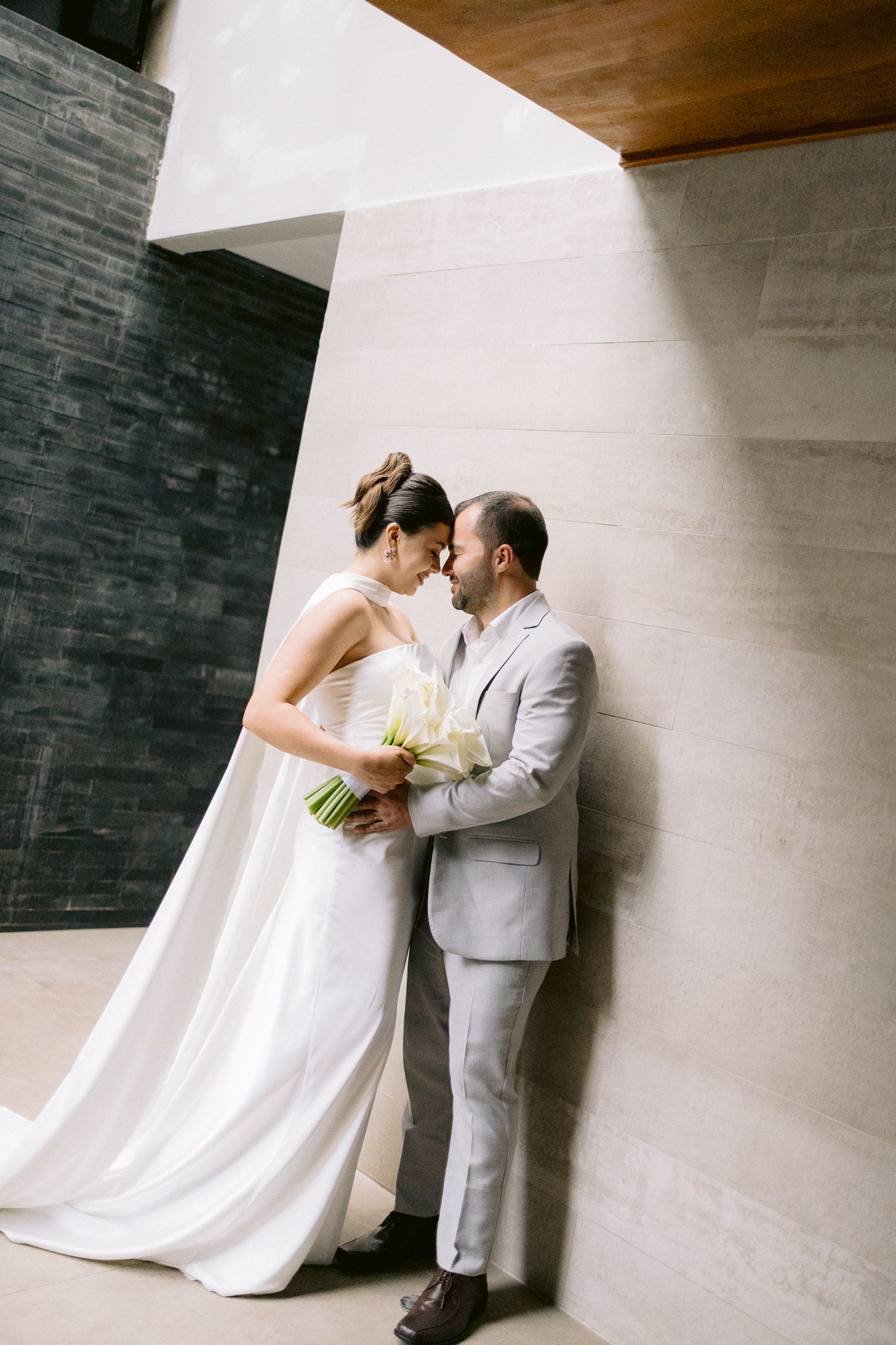 Romantic wedding couple poses against a minimalist wall in an artistic sequence.