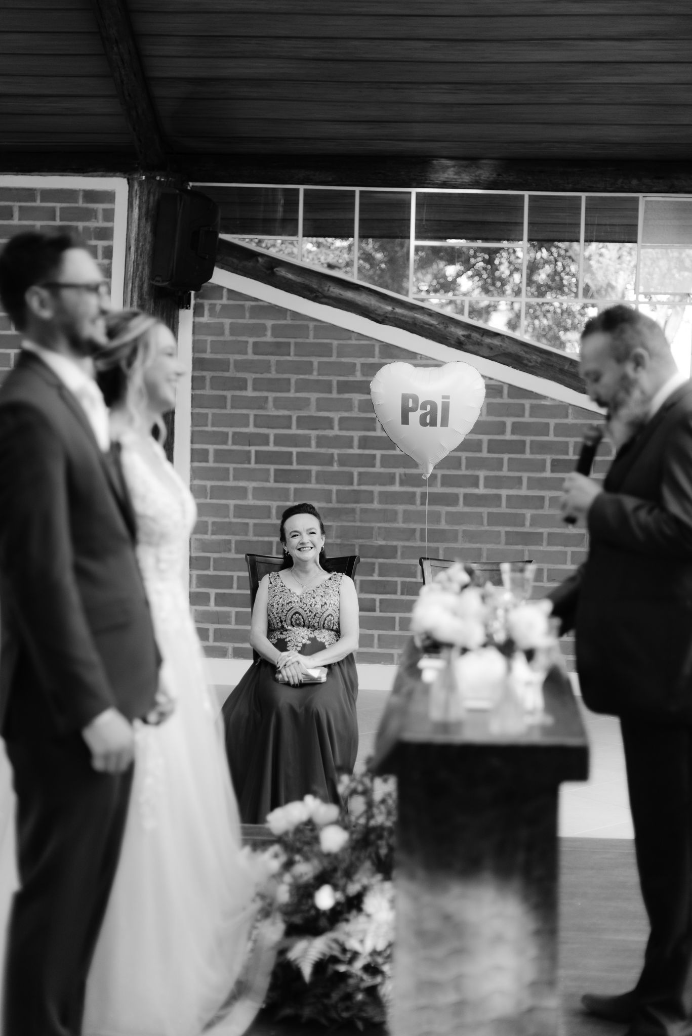 Black and white photo of a wedding ceremony with people gathered under a brick structure.