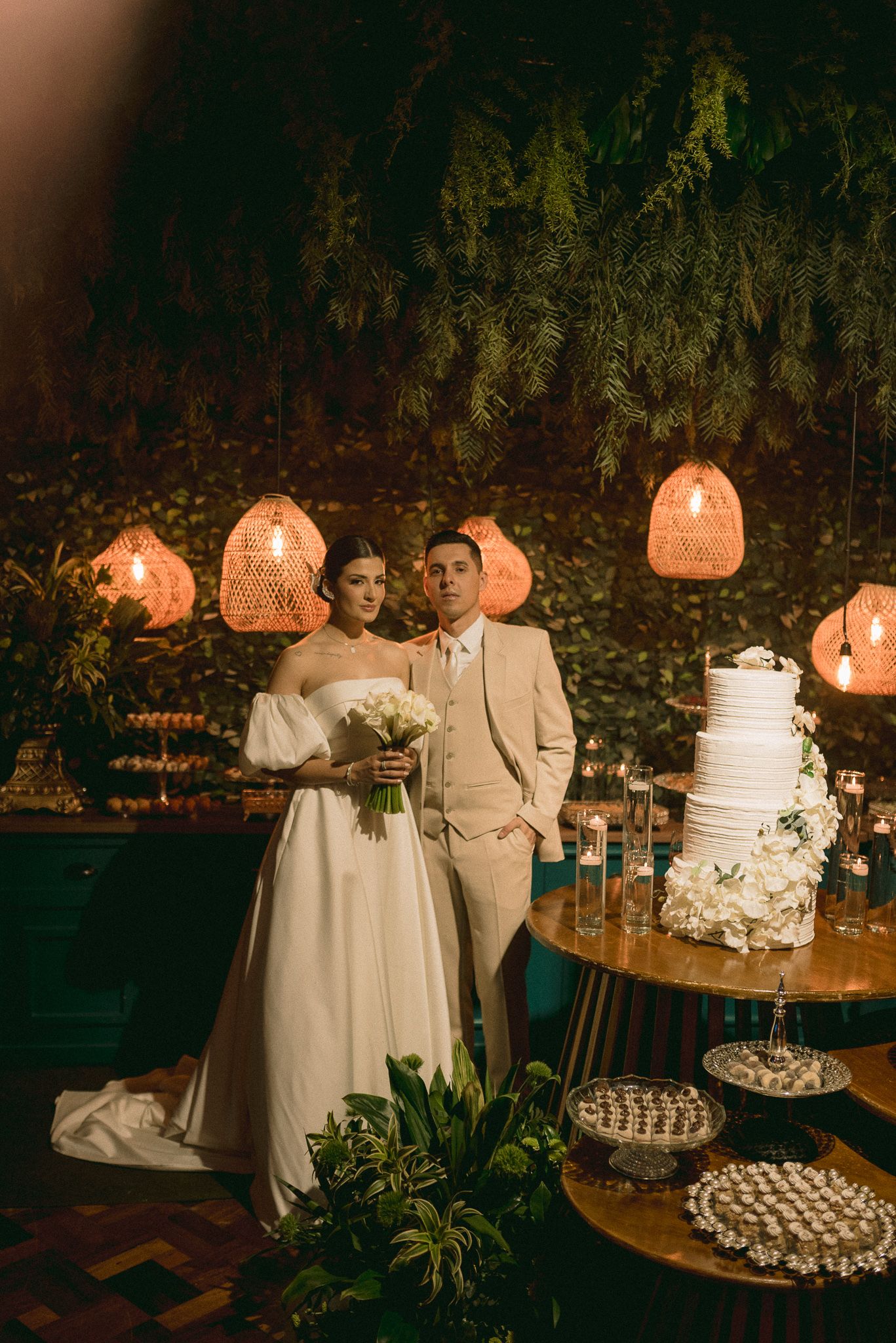 Wedding cake and dessert display with coral lanterns creating a romantic evening ambiance.
